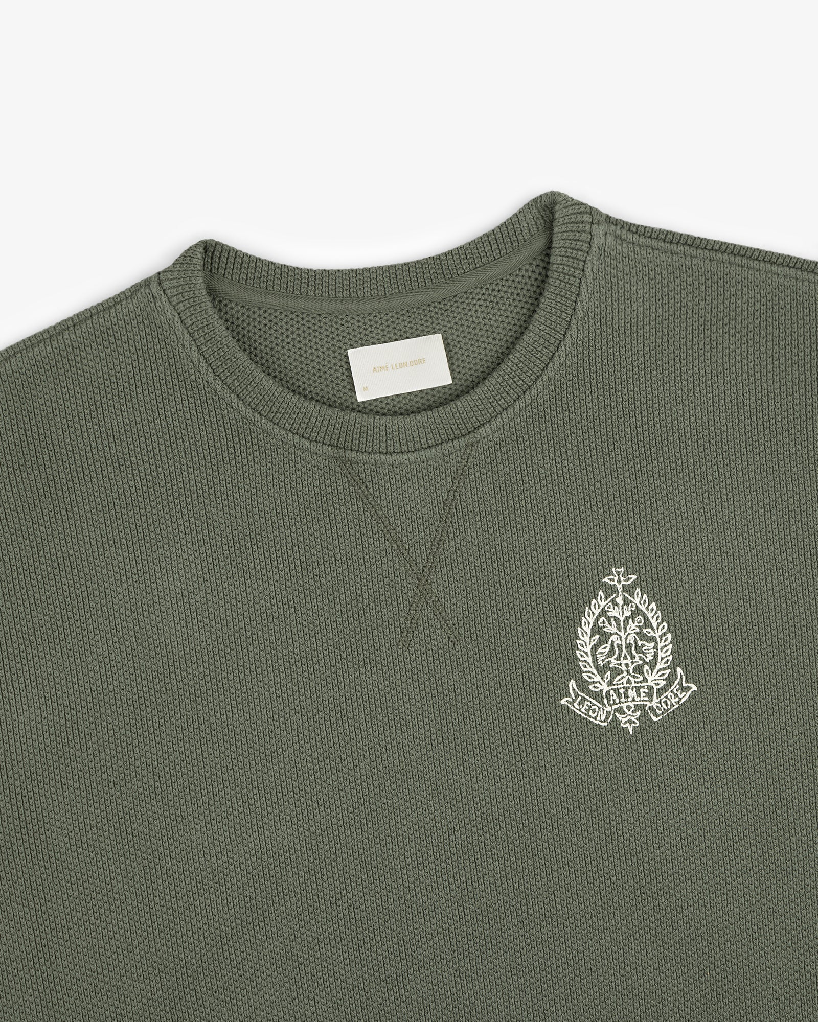 Saint George Piqué Crewneck Sweatshirt in olive with white embroidered crest on chest and visible neck label.