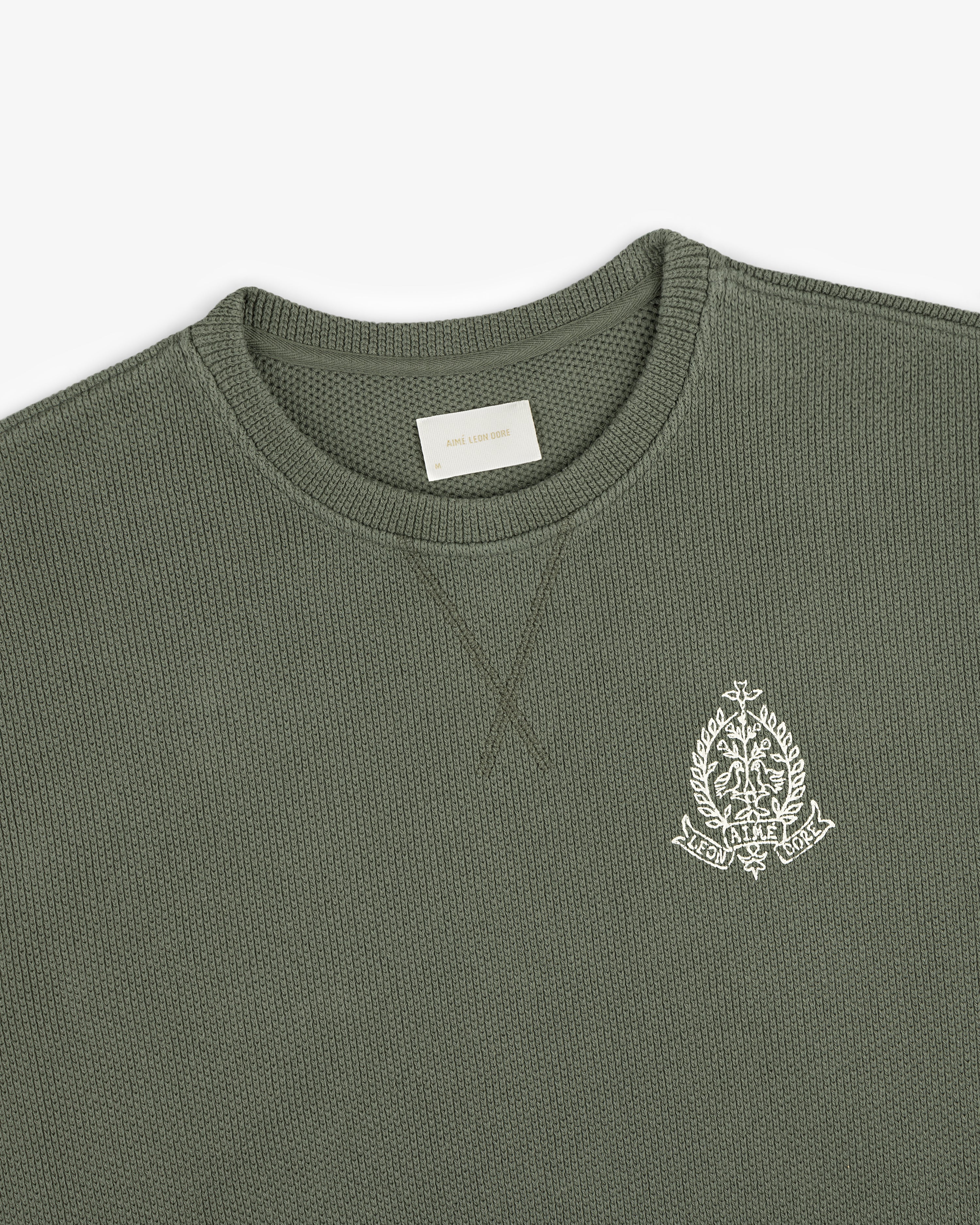 Saint George Piqué Crewneck Sweatshirt in olive with white embroidered crest on chest and visible neck label.