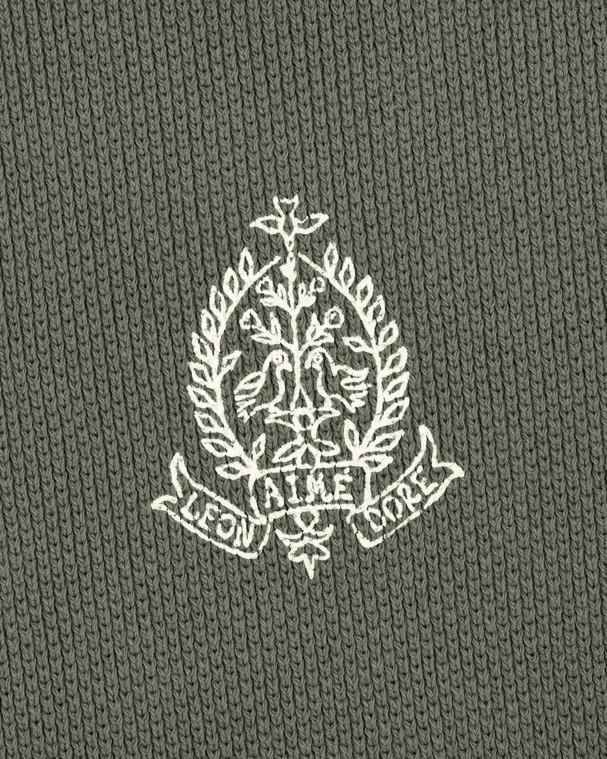 White crest with birds, branches, and AIME LEON DORE text on green Saint George Piqué Crewneck Sweatshirt.