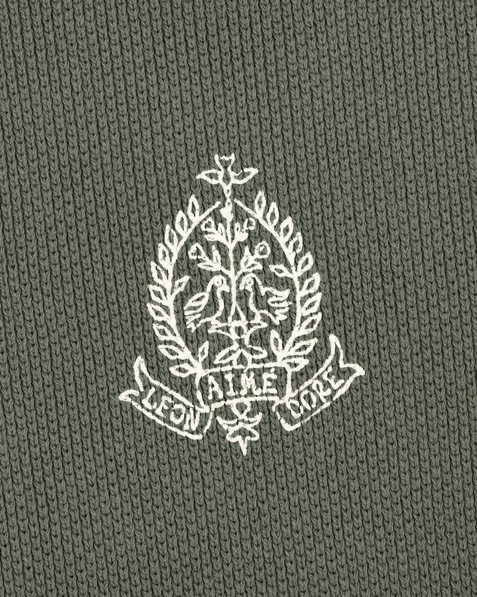 White crest with birds, branches, and AIME LEON DORE text on green Saint George Piqué Crewneck Sweatshirt.