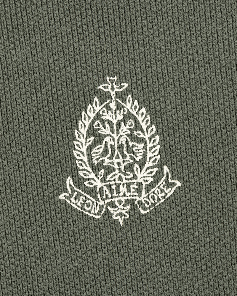 White crest with birds, branches, and AIME LEON DORE text on green Saint George Piqué Crewneck Sweatshirt.