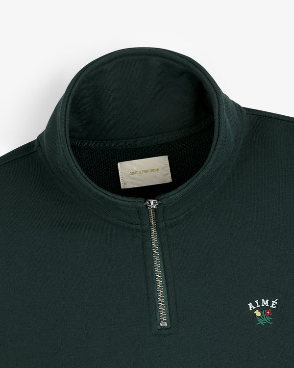 Dark green Crest Quarter Zip Pullover with AIMÉ and rose embroidery on the chest.