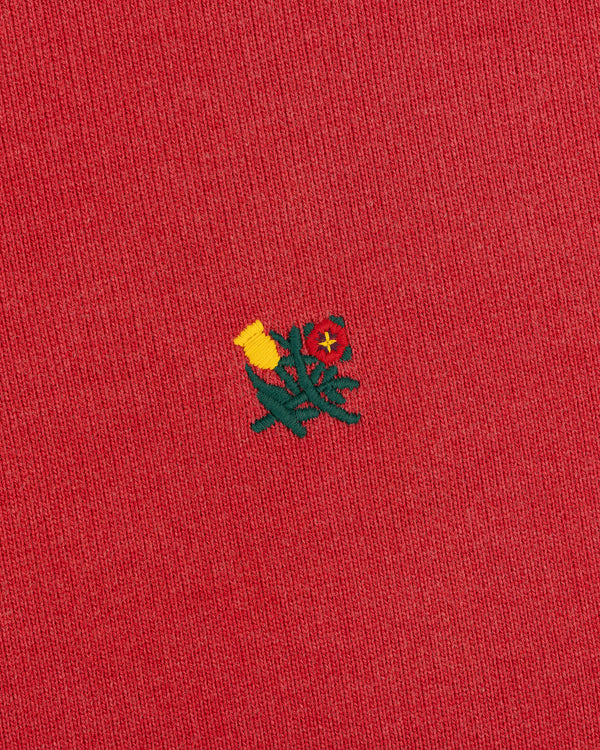 Yellow and red flower embroidery on Sun Faded Crest Quarter Zip's red fabric.
