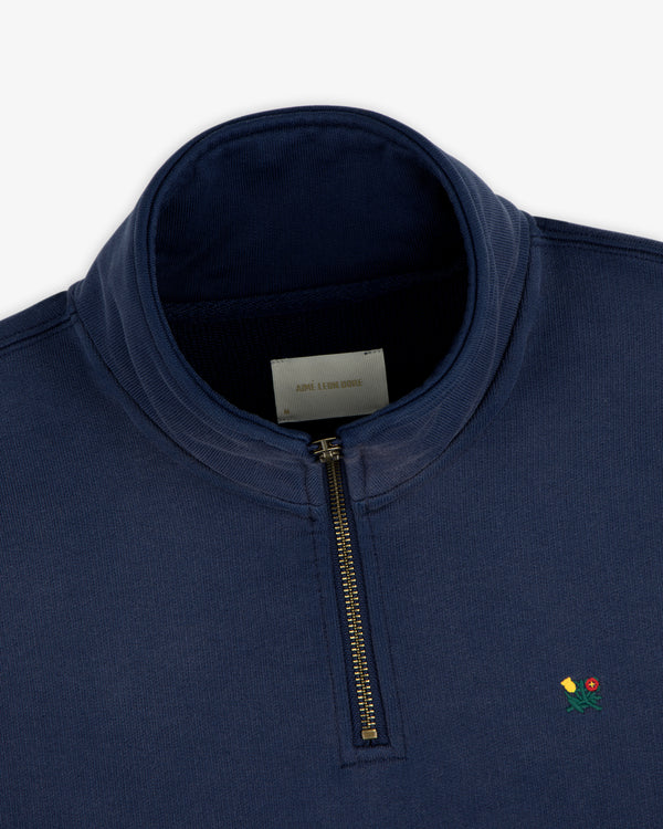Sun Faded Crest Quarter Zip in navy blue with small yellow and red flower embroidery on the left chest.