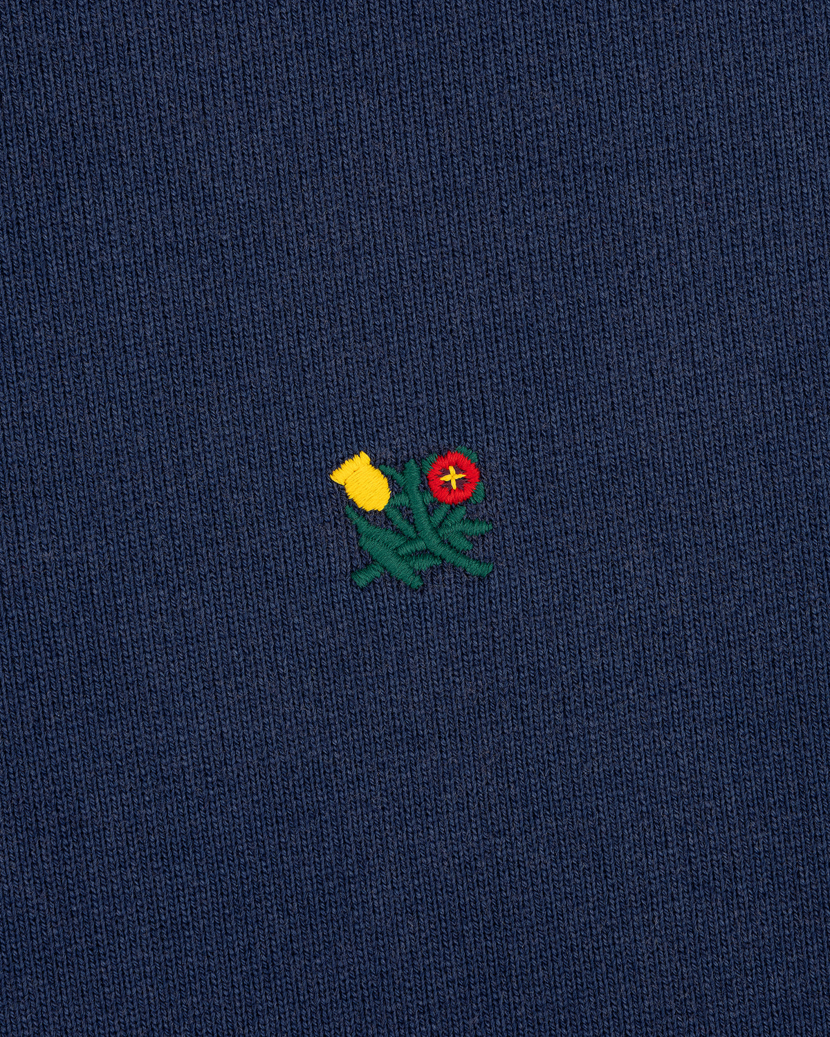 Small yellow and red embroidered flowers with green stems adorn the Sun Faded Crest Quarter Zip’s navy blue knit.