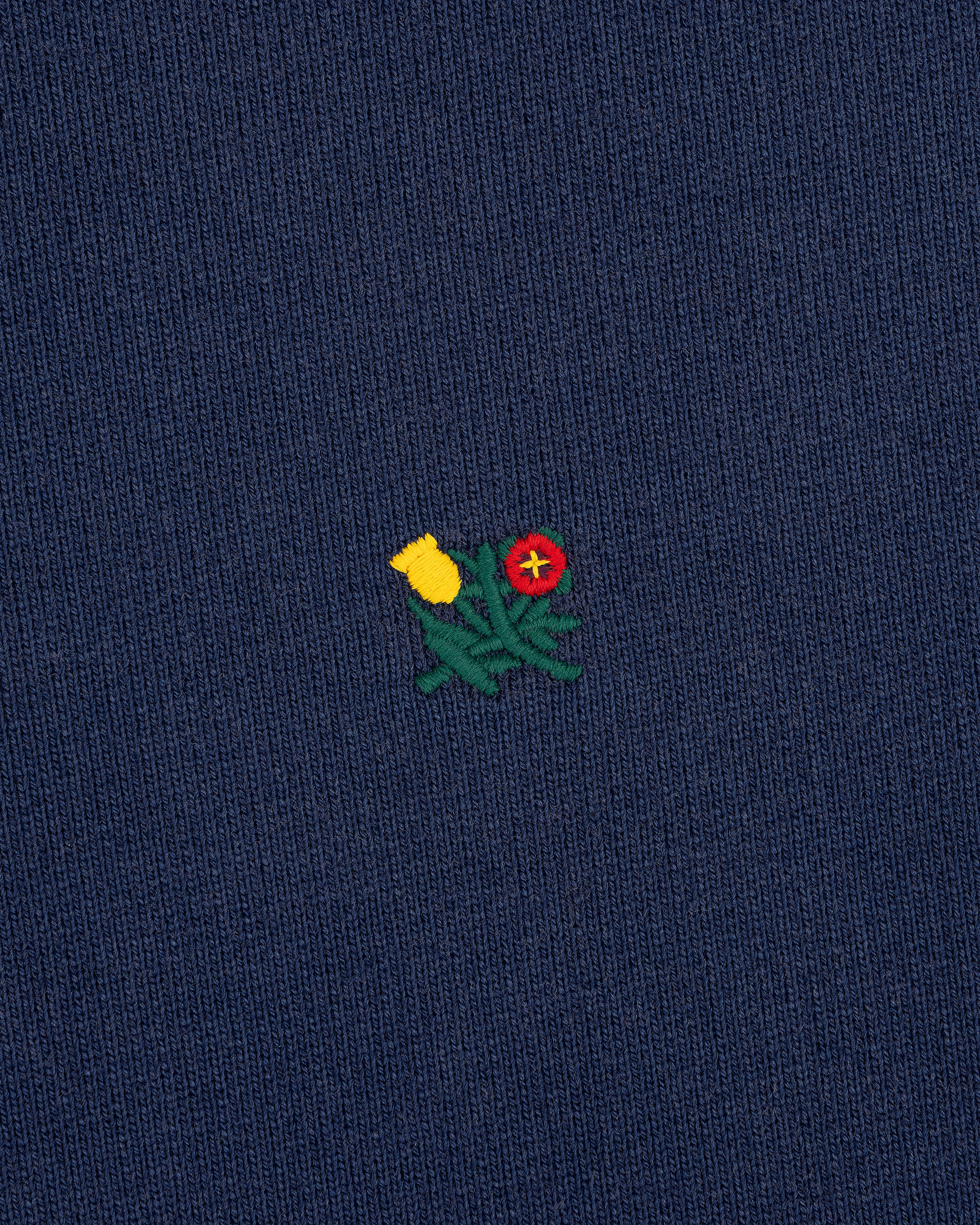 Small yellow and red embroidered flowers with green stems adorn the Sun Faded Crest Quarter Zip’s navy blue knit.
