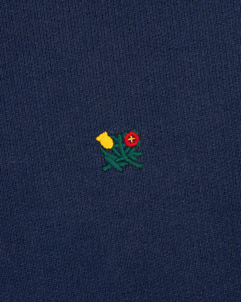 Small yellow and red embroidered flowers with green stems adorn the Sun Faded Crest Quarter Zip’s navy blue knit.