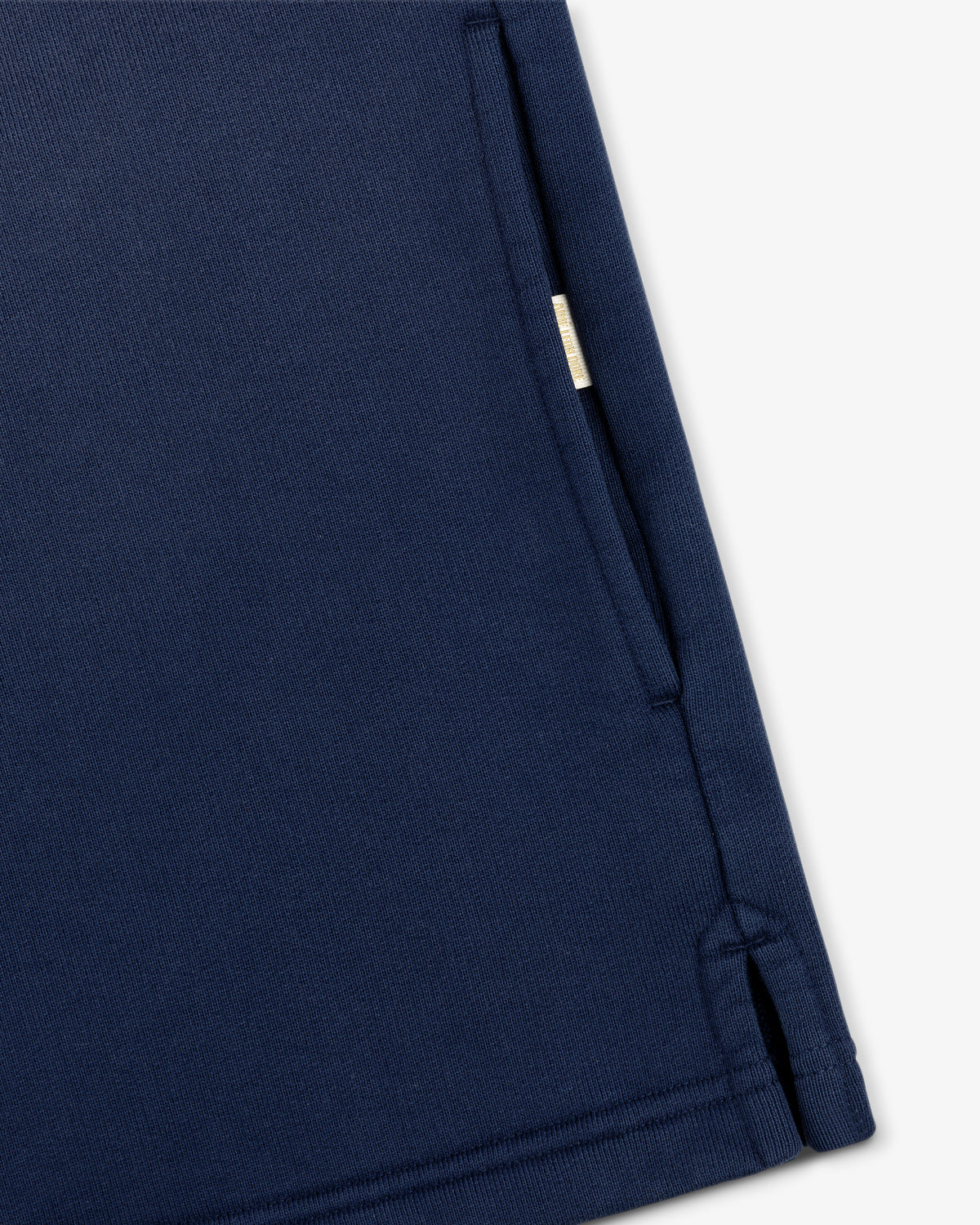 Close-up of the Sun Faded Crest Quarter Zip's navy pocket with a small beige tag and visible edge stitching.