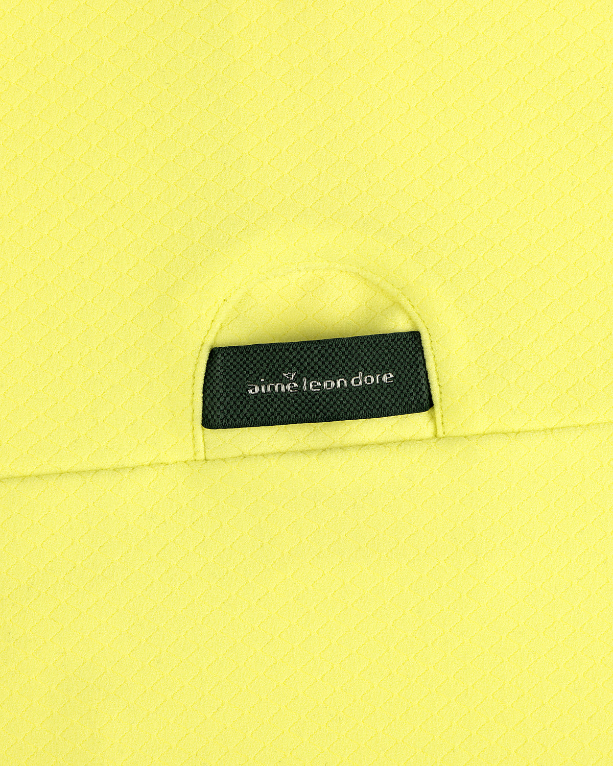 Close-up of yellow ALD Golf Quarter Zip Pullover with a small black aime leon dore label tucked into the pocket.