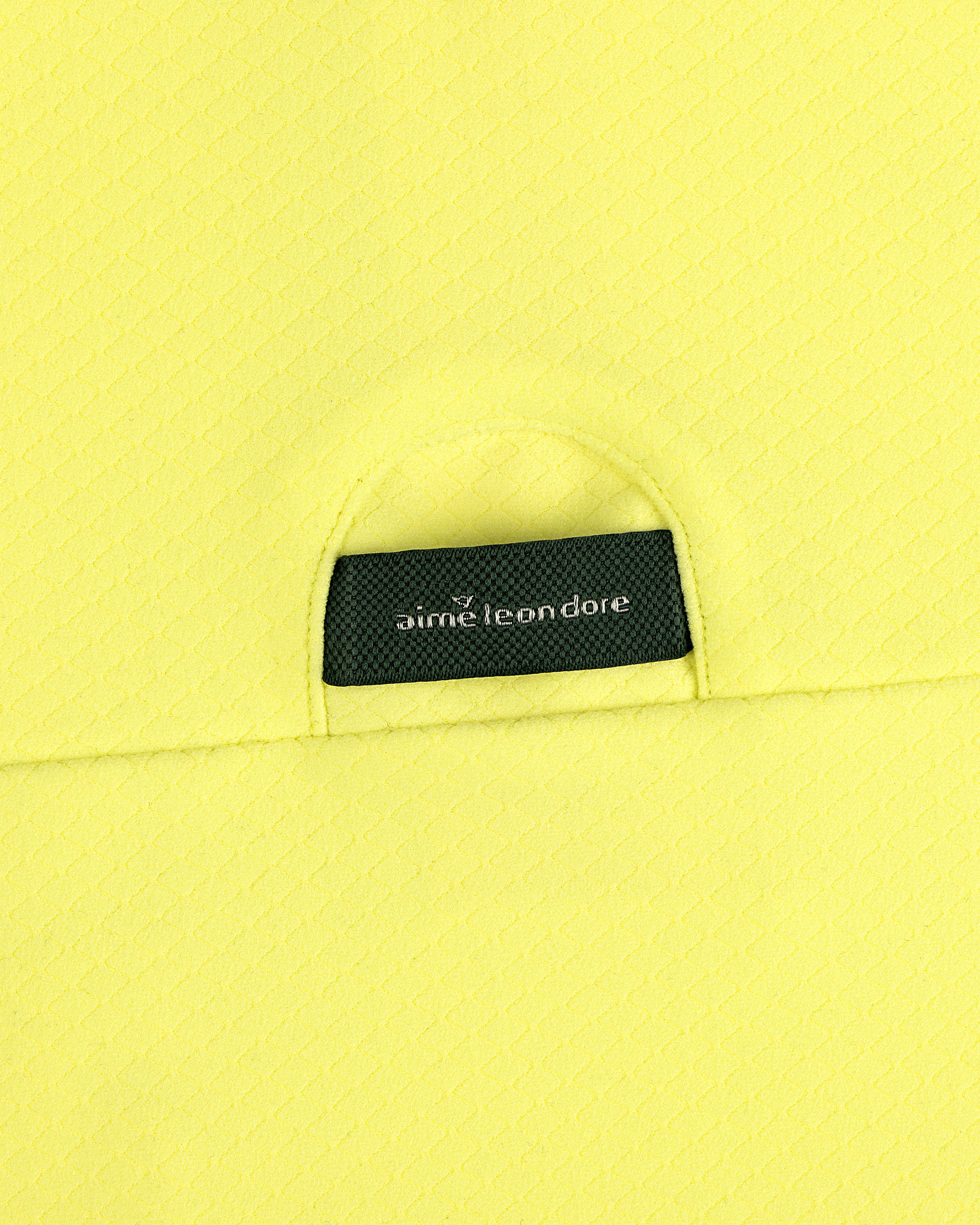 Close-up of yellow ALD Golf Quarter Zip Pullover with a small black aime leon dore label tucked into the pocket.