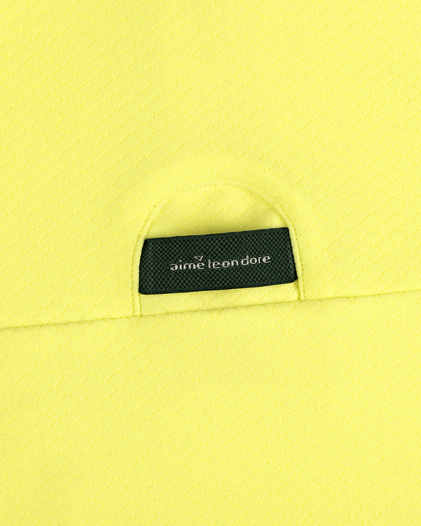 Close-up of yellow ALD Golf Quarter Zip Pullover with a small black aime leon dore label tucked into the pocket.