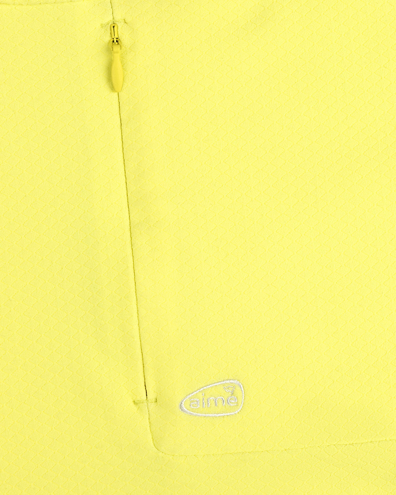 Close-up of ALD Golf Quarter Zip Pullover in yellow with textured fabric, zip pocket, and white aimé logo embroidery.