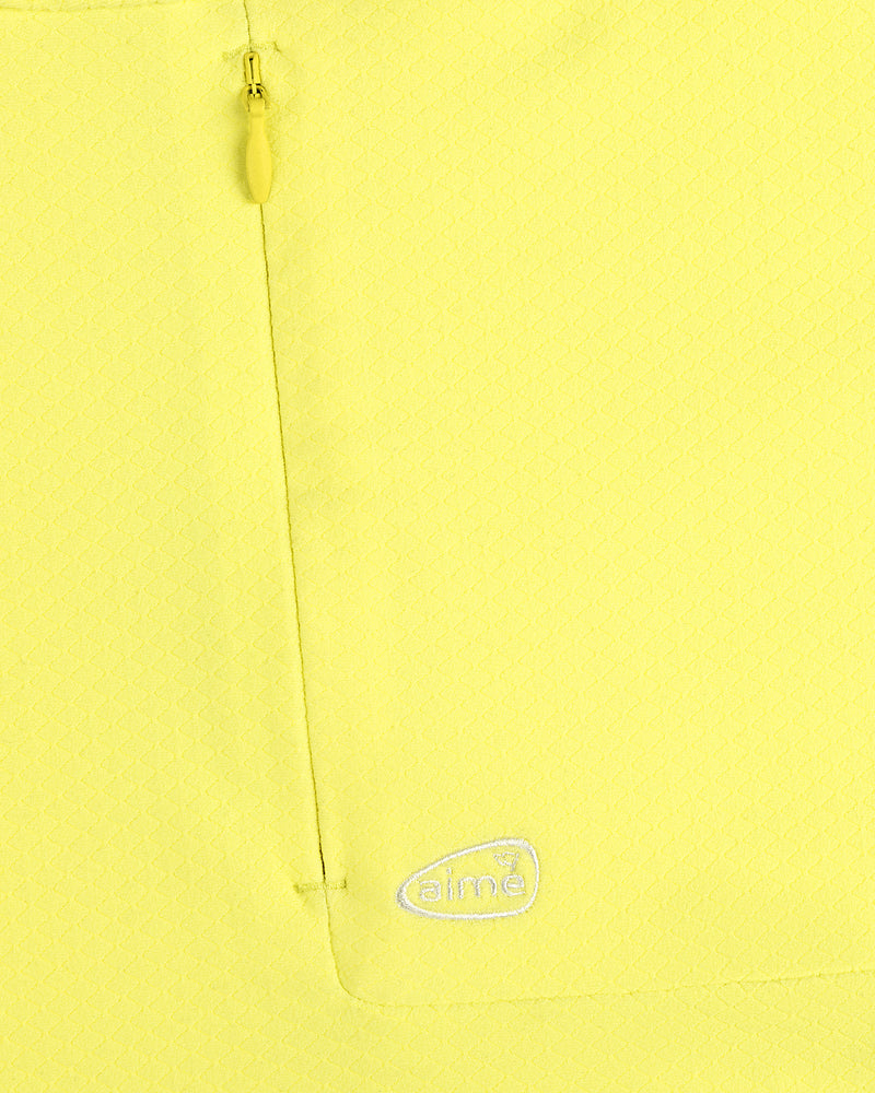 Close-up of ALD Golf Quarter Zip Pullover in yellow with textured fabric, zip pocket, and white aimé logo embroidery.