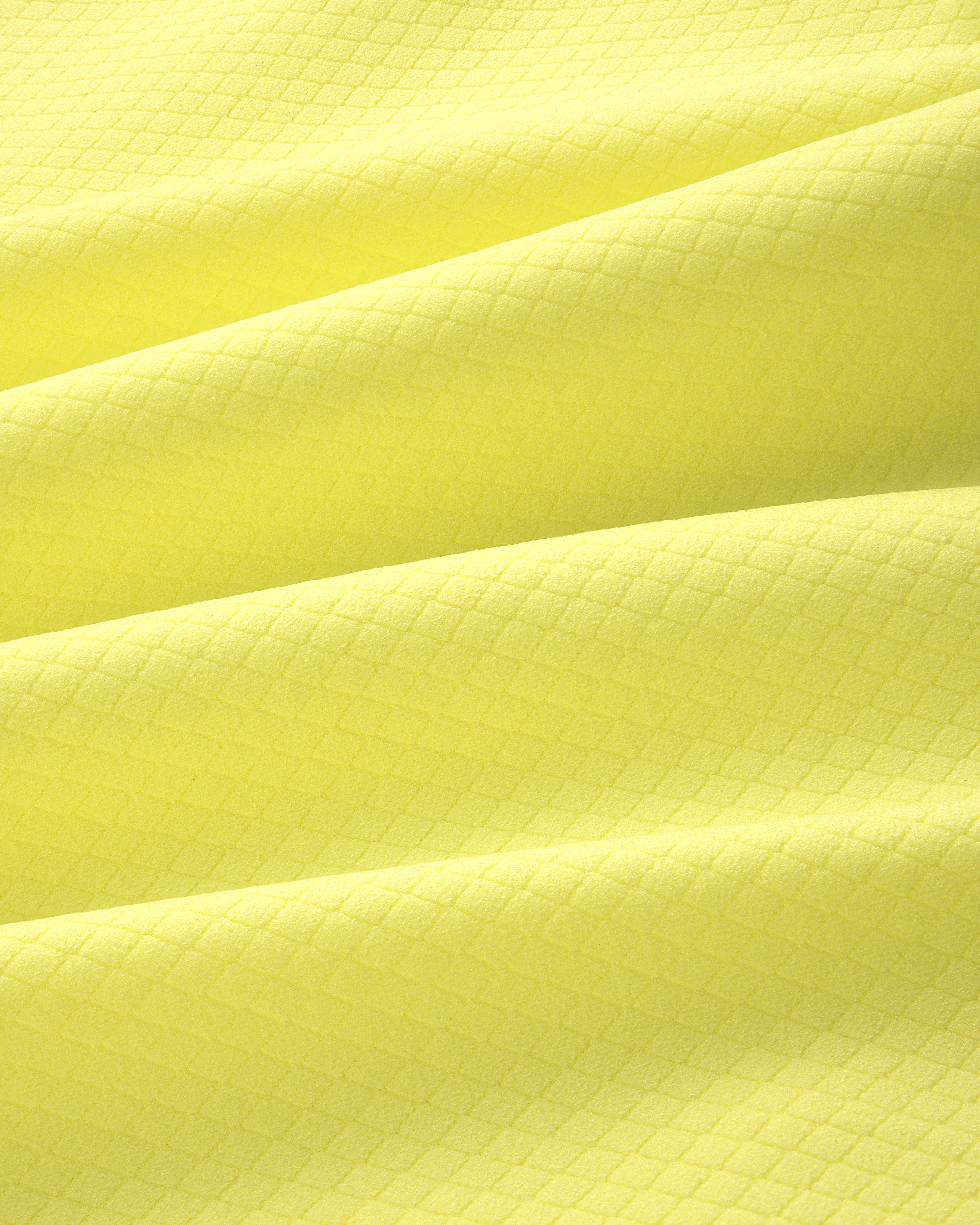 Close-up of yellow ALD Golf Quarter Zip Pullover fabric with a subtle diamond pattern and gentle folds.