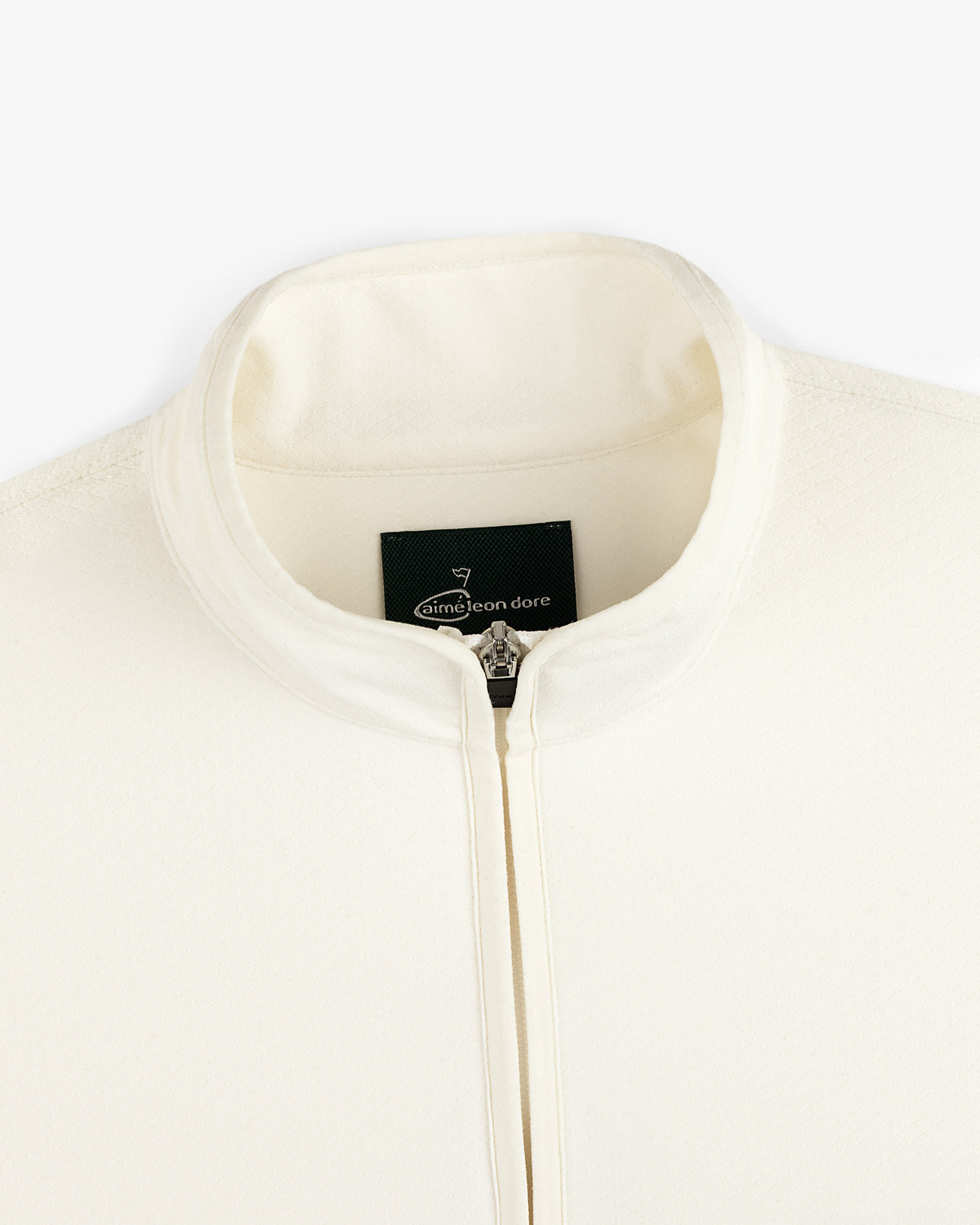 Close-up of the cream ALD Golf Quarter Zip Pullover with a stand collar and visible Aimé Leon Dore tag inside.