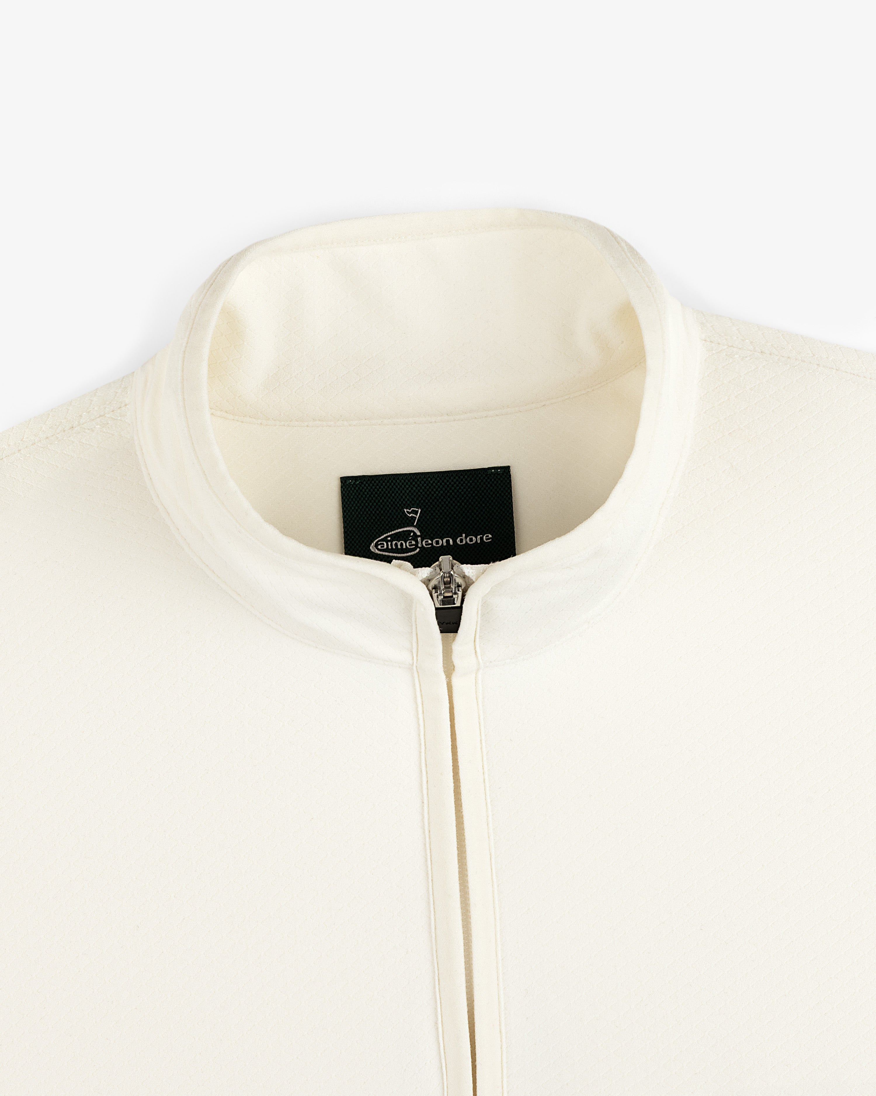 Close-up of the cream ALD Golf Quarter Zip Pullover with a stand collar and visible Aimé Leon Dore tag inside.