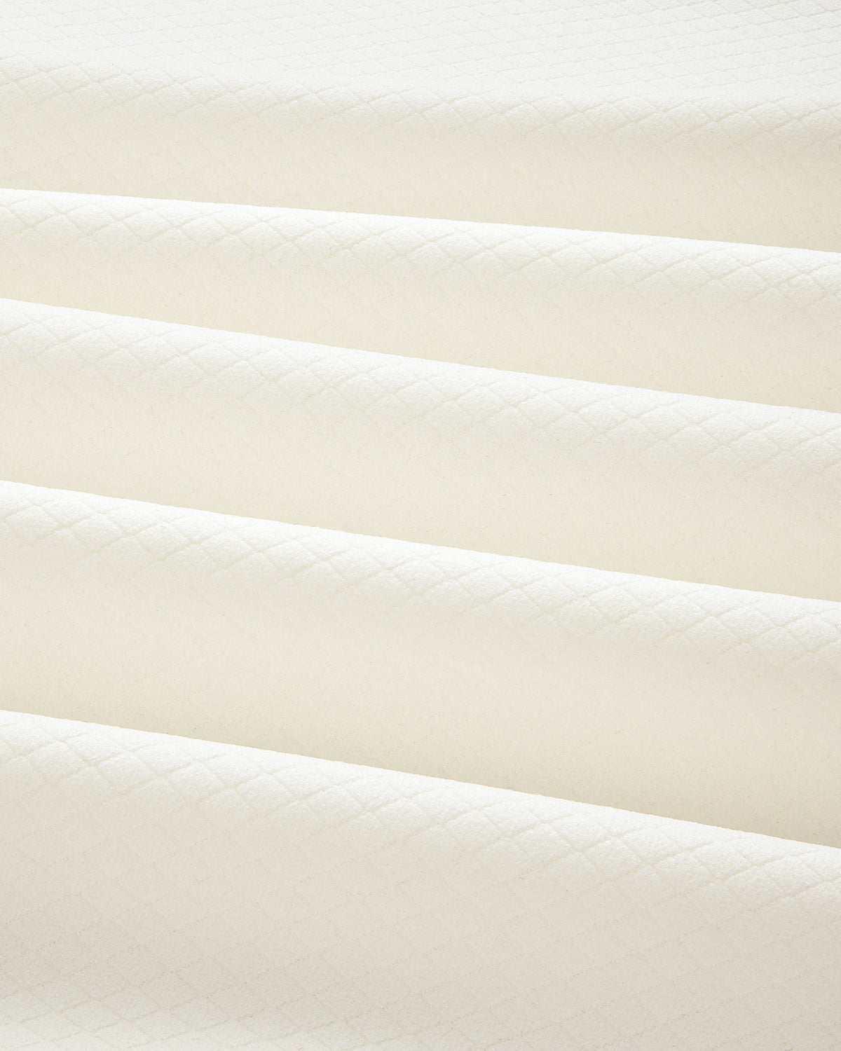 Close-up of folded ALD Golf Quarter Zip Pullover in cream with a subtle diamond pattern and soft shadows.
