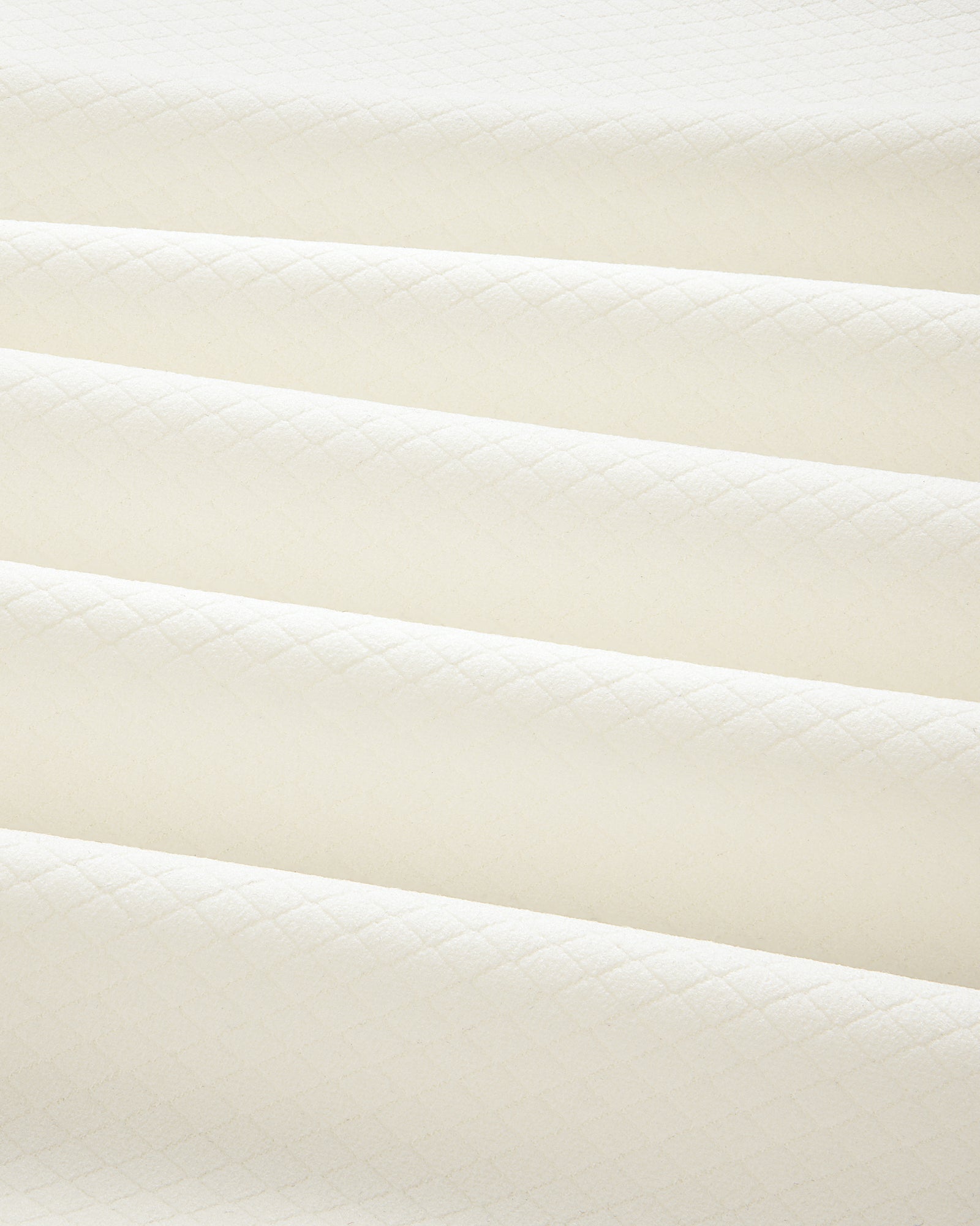 Close-up of folded ALD Golf Quarter Zip Pullover in cream with a subtle diamond pattern and soft shadows.