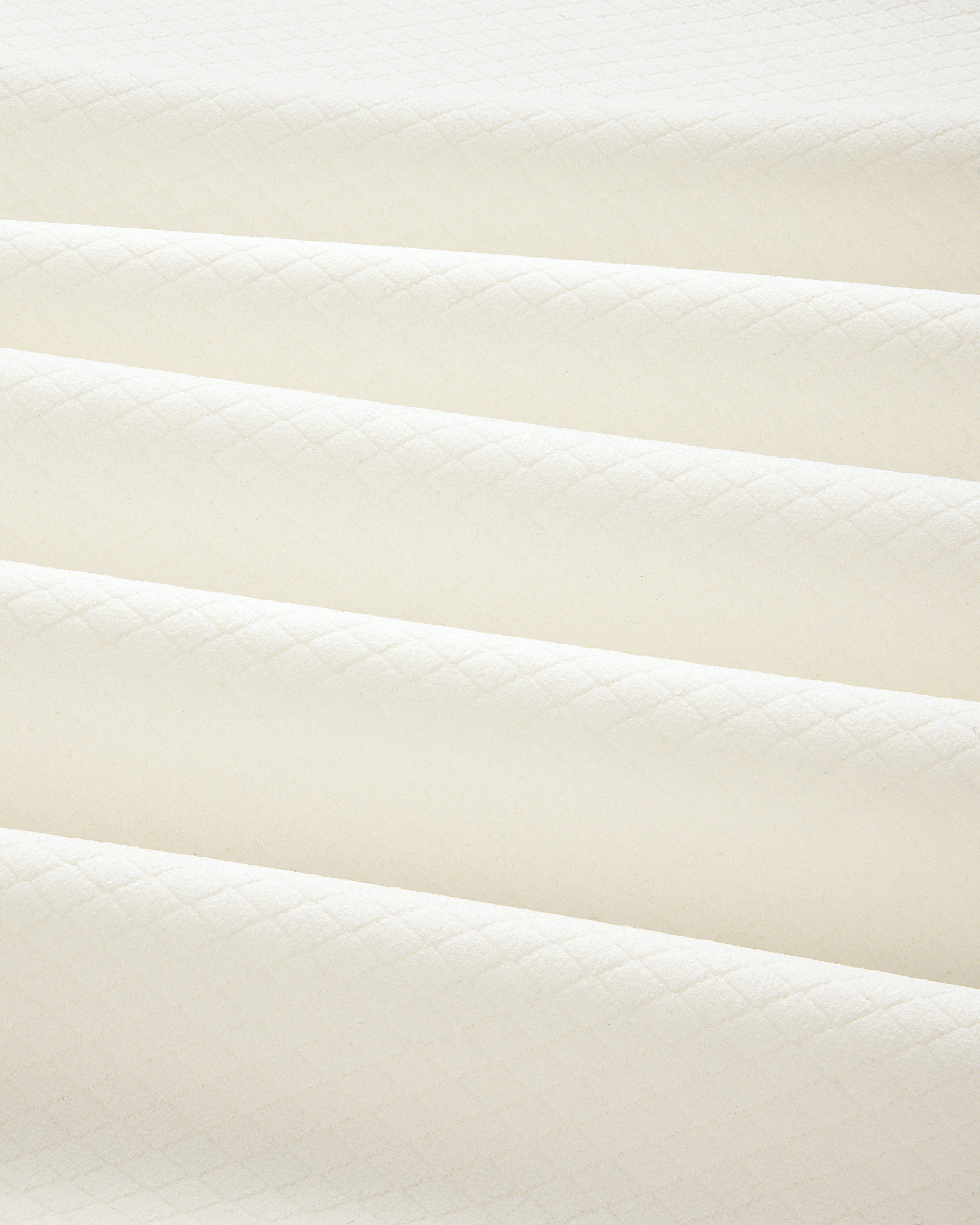 Close-up of folded ALD Golf Quarter Zip Pullover in cream with a subtle diamond pattern and soft shadows.