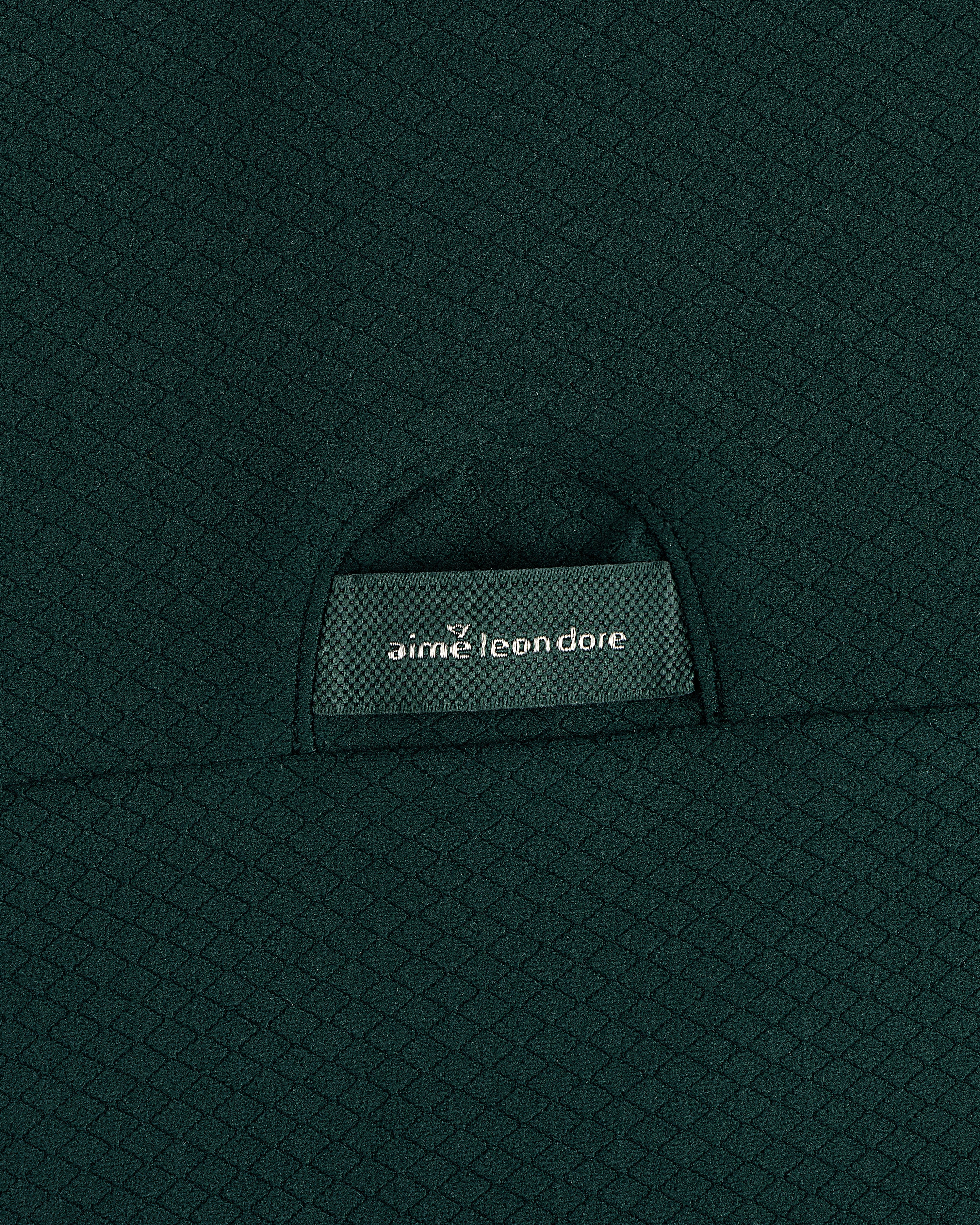Close-up of green textured fabric on the ALD Golf Quarter Zip Pullover with an aime leon dore label on a small pocket.
