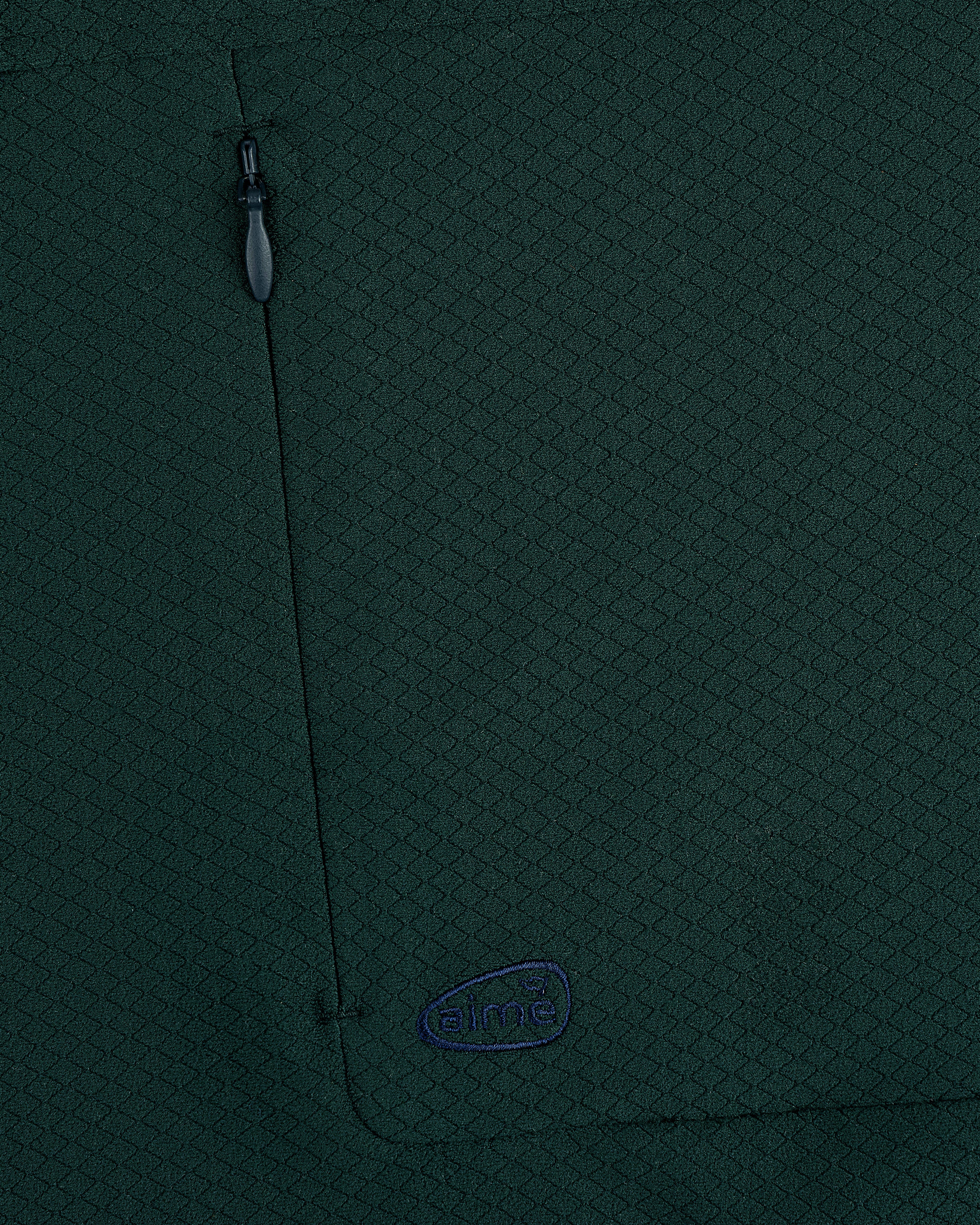Close-up of dark green ALD Golf Quarter Zip Pullover with zipper pocket and small blue aimé embroidered logo.