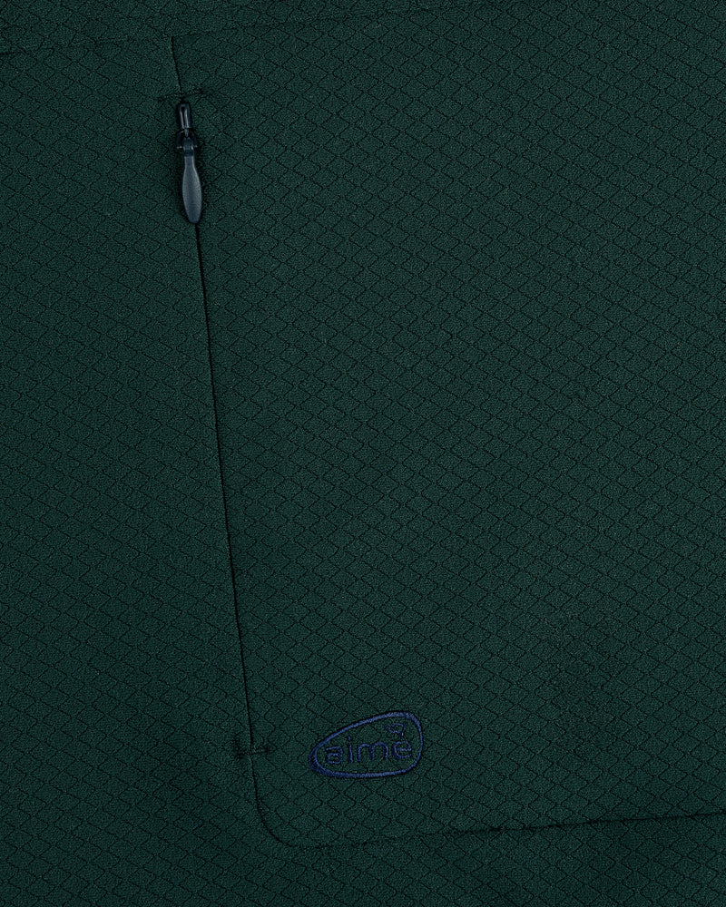 Close-up of dark green ALD Golf Quarter Zip Pullover with zipper pocket and small blue aimé embroidered logo.