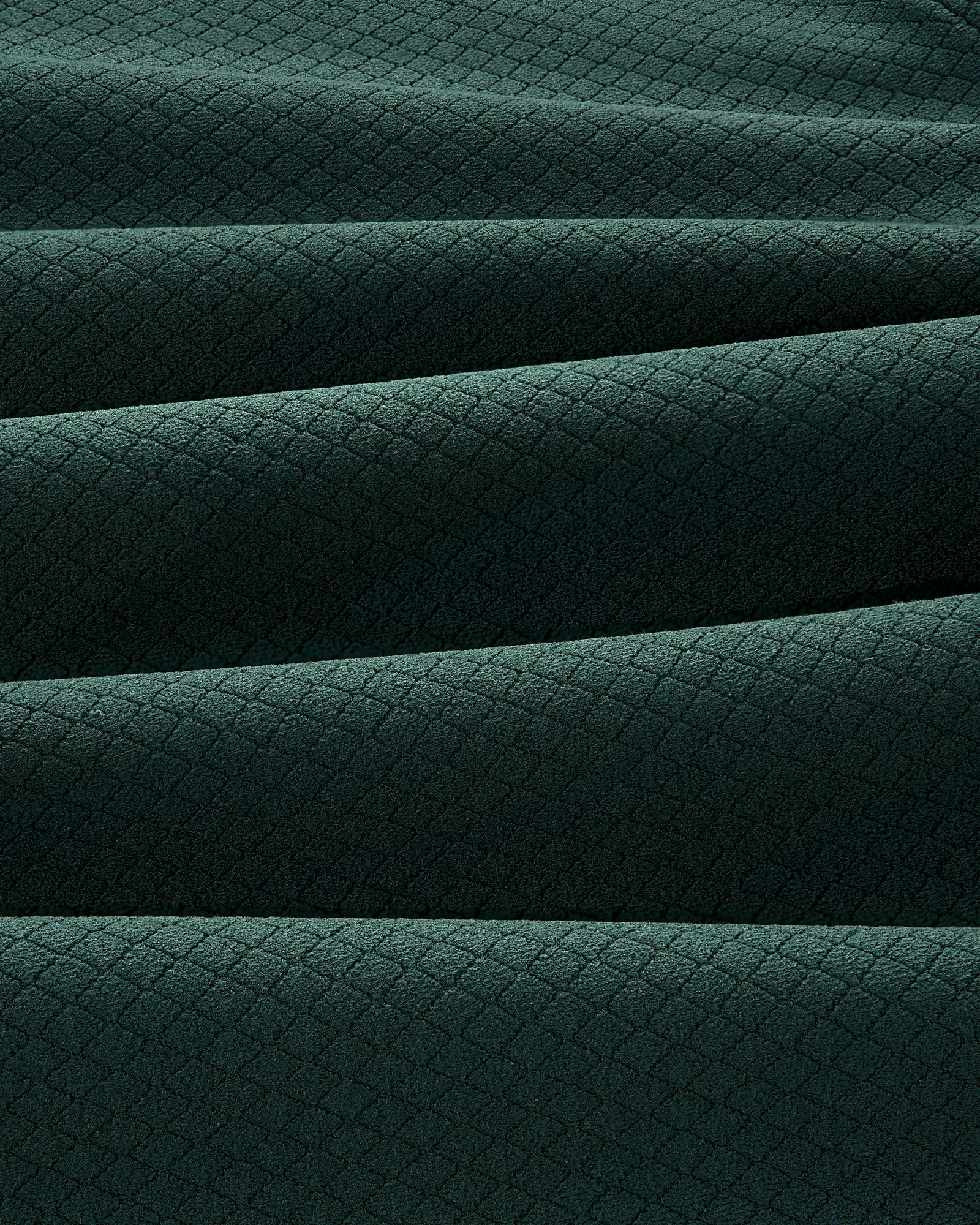 Close-up of folded ALD Golf Quarter Zip Pullover in dark green with a small diamond pattern texture.