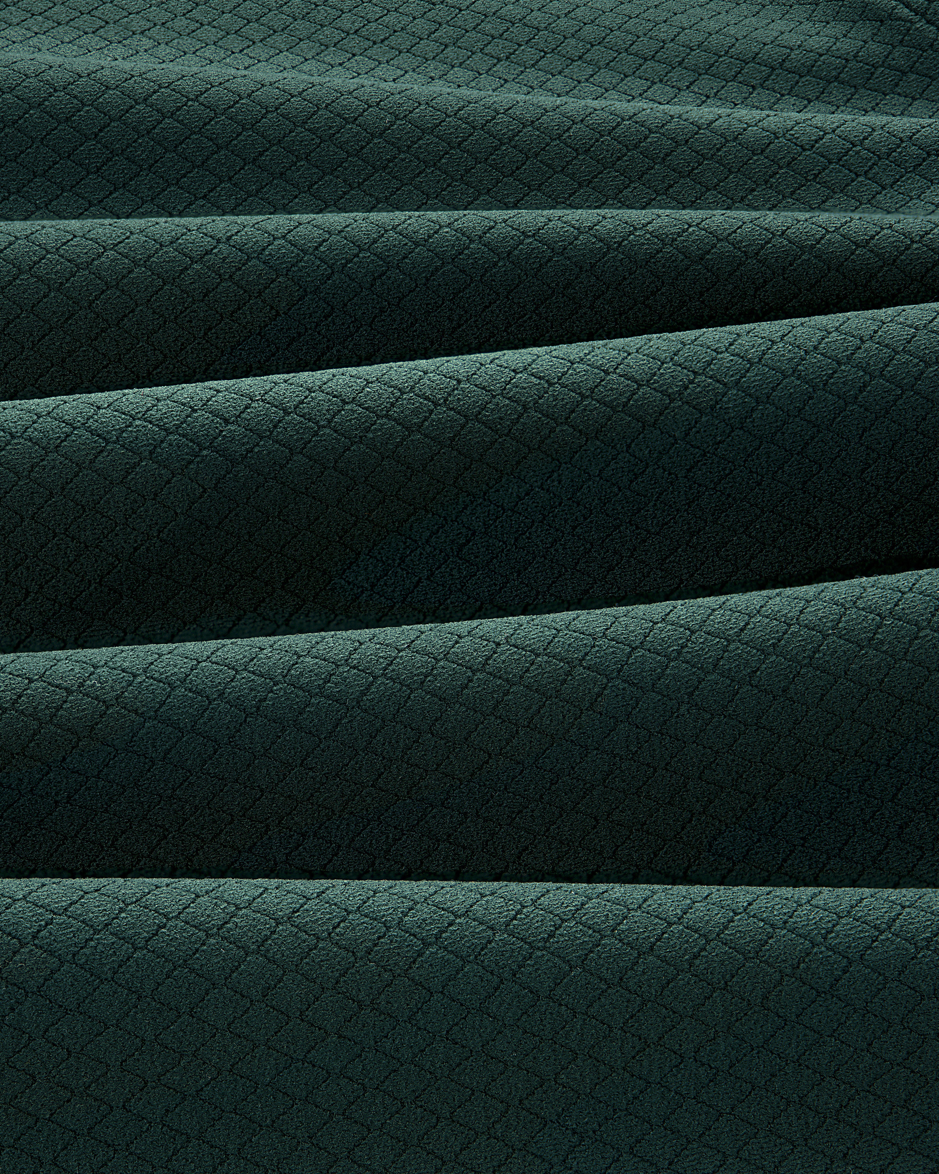 Close-up of folded ALD Golf Quarter Zip Pullover in dark green with a small diamond pattern texture.