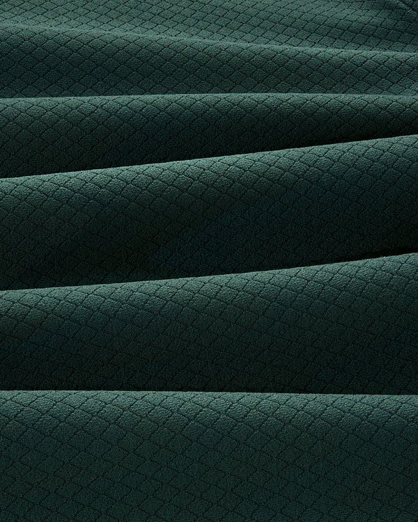 Close-up of folded ALD Golf Quarter Zip Pullover in dark green with a small diamond pattern texture.