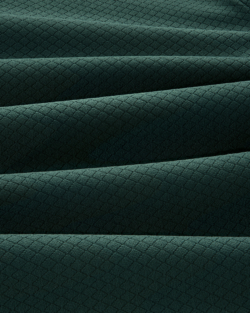 Close-up of folded ALD Golf Quarter Zip Pullover in dark green with a small diamond pattern texture.