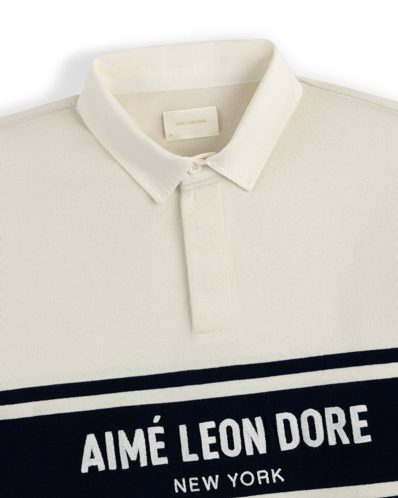 Cream-colored Chest Stripe Logo Rugby with AIMÉ LEON DORE NEW YORK in white on a navy chest stripe.