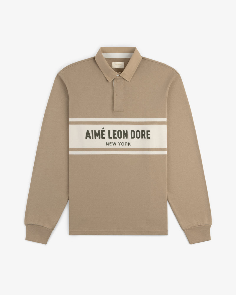 Beige Chest Stripe Logo Rugby with “AIMÉ LEON DORE NEW YORK” text in white and black across the chest.