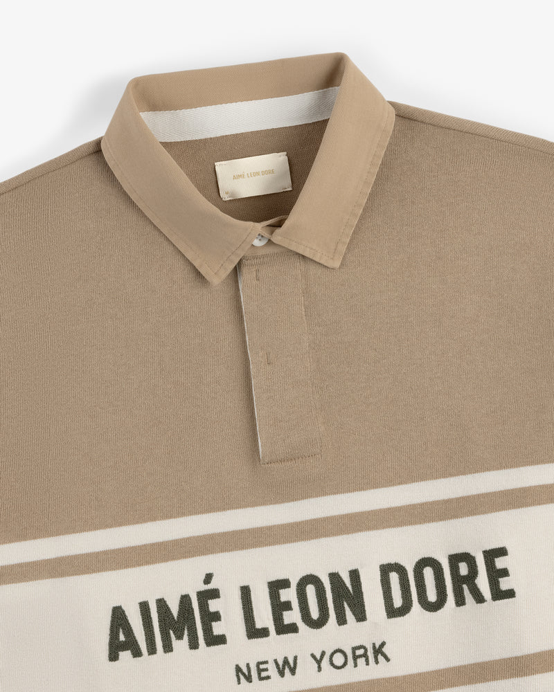 Chest Stripe Logo Rugby with beige collar, white chest stripes, and AIMÉ LEON DORE NEW YORK text.