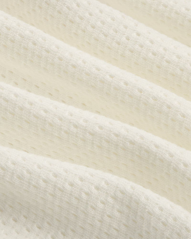 Close-up of the Pointelle Stacked Logo Tee's soft, white textured fabric with small perforations and wavy folds.