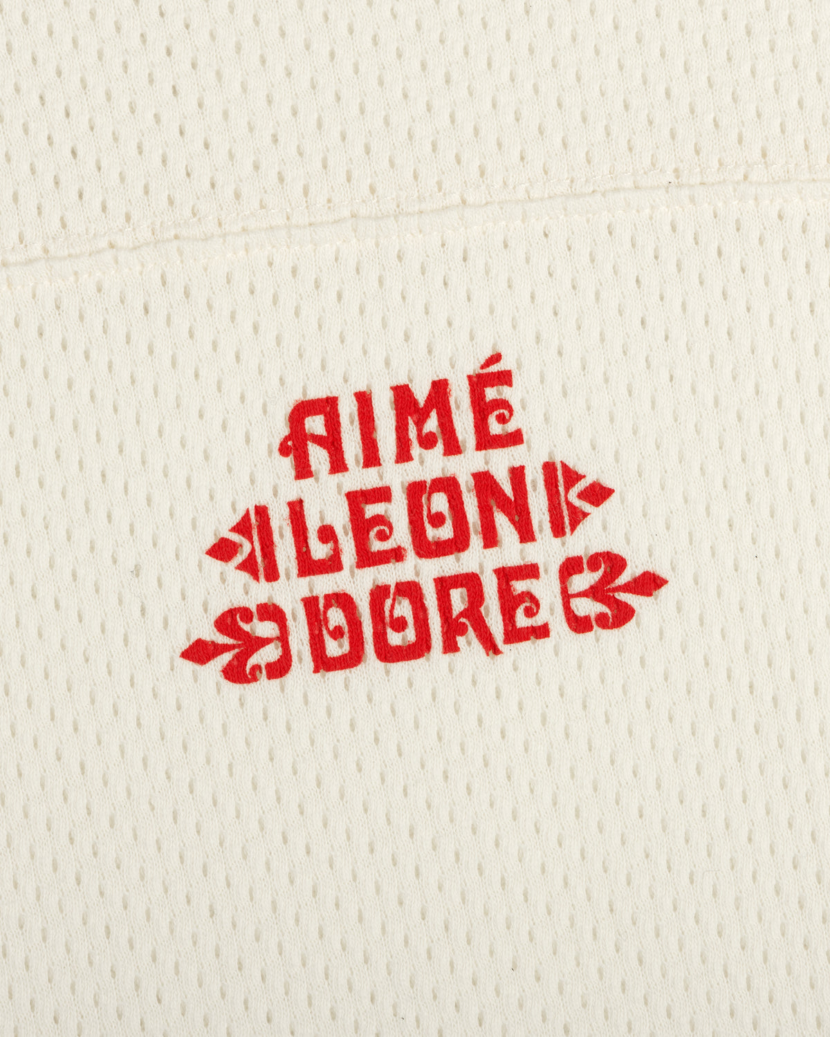 Cream Pointelle Stacked Logo Tee with red AIMÉ LEON DORE text printed in the center.