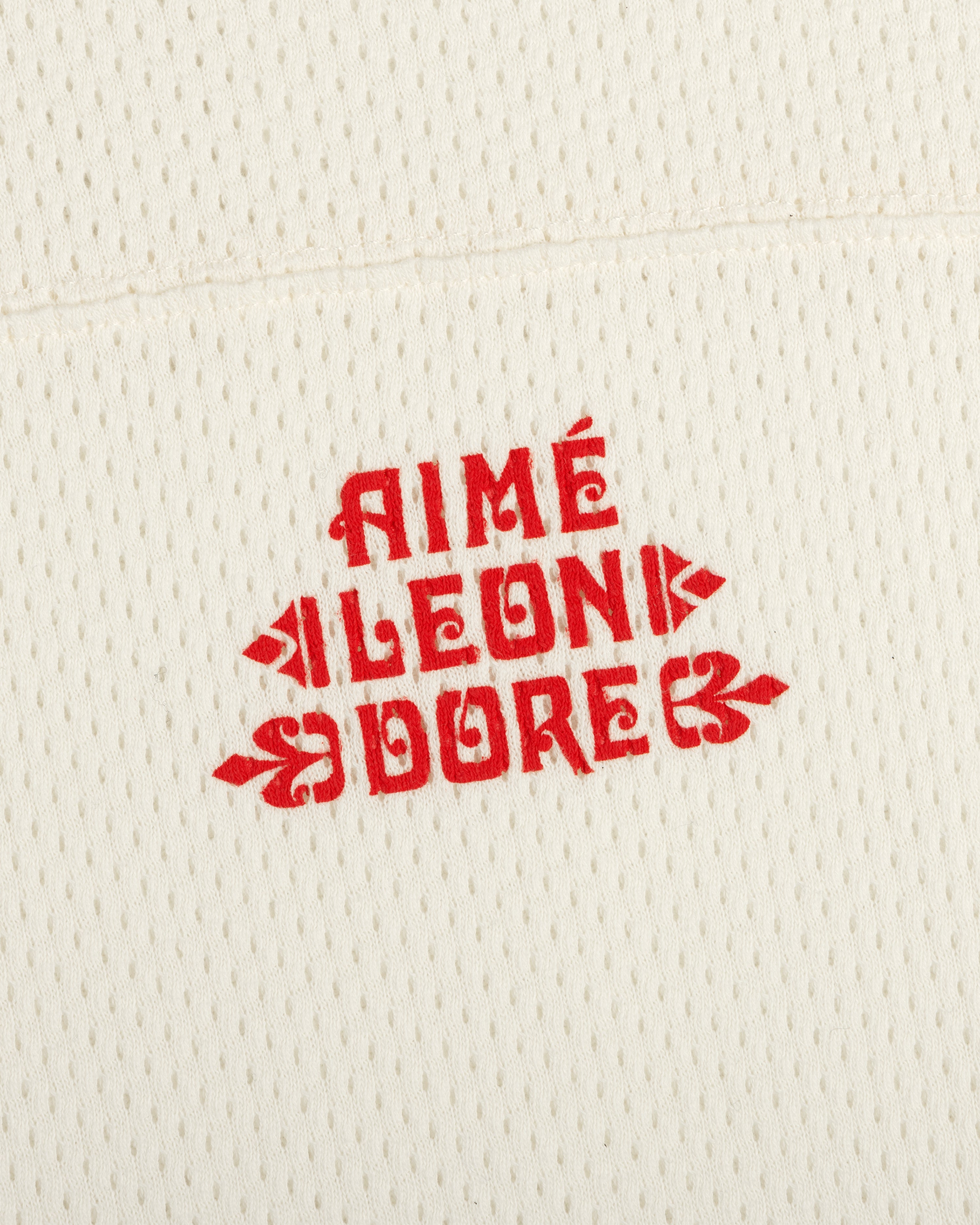 Cream Pointelle Stacked Logo Tee with red AIMÉ LEON DORE text printed in the center.