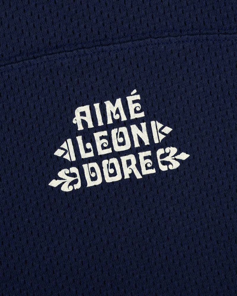 Close-up of white Pointelle Stacked Logo Tee text on navy blue mesh fabric.