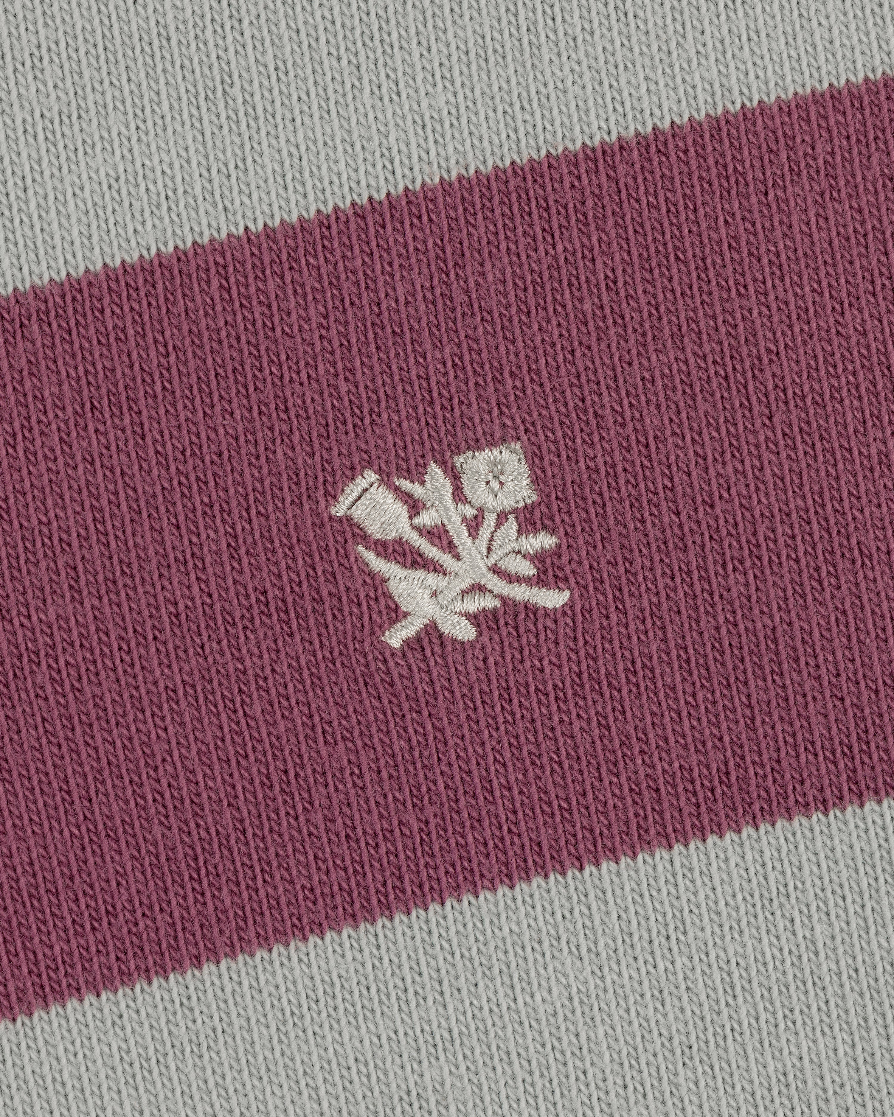 Close-up of the Striped Crest Rugby: maroon and gray stripes with a white embroidered floral design in the center.