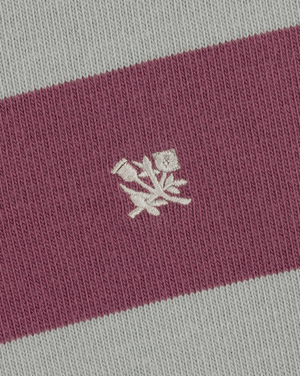 Close-up of the Striped Crest Rugby: maroon and gray stripes with a white embroidered floral design in the center.