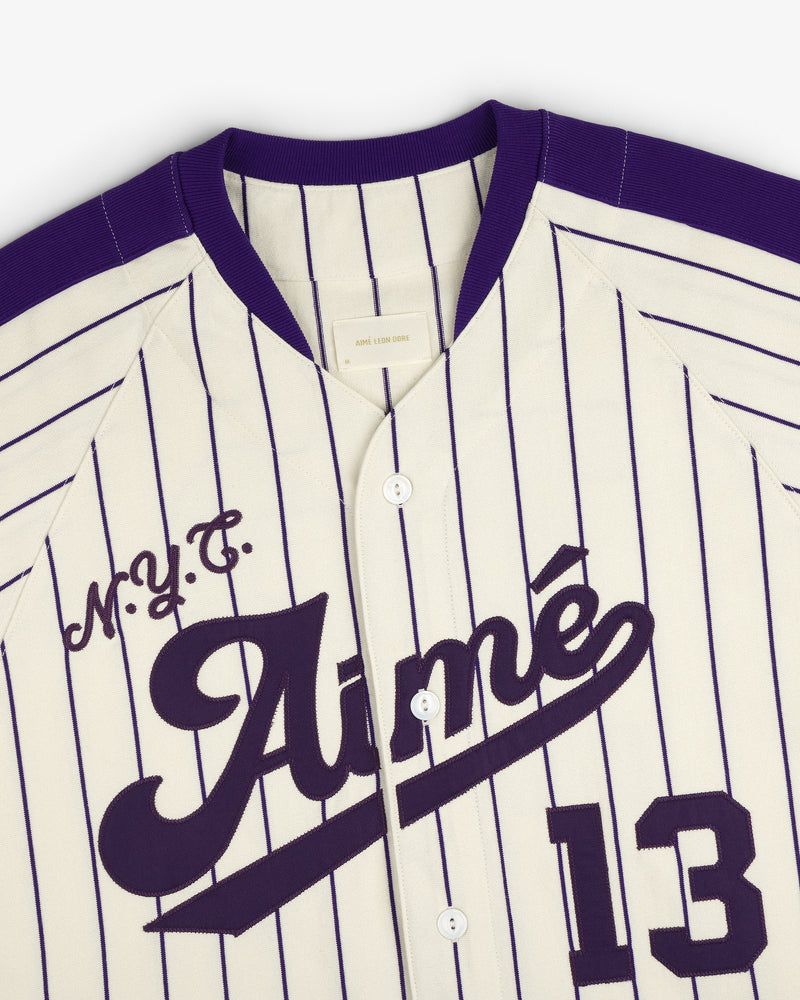 Aimé Baseball Jersey in cream and purple pinstripes with M.Y.C. Aimé and number 13 on the front.