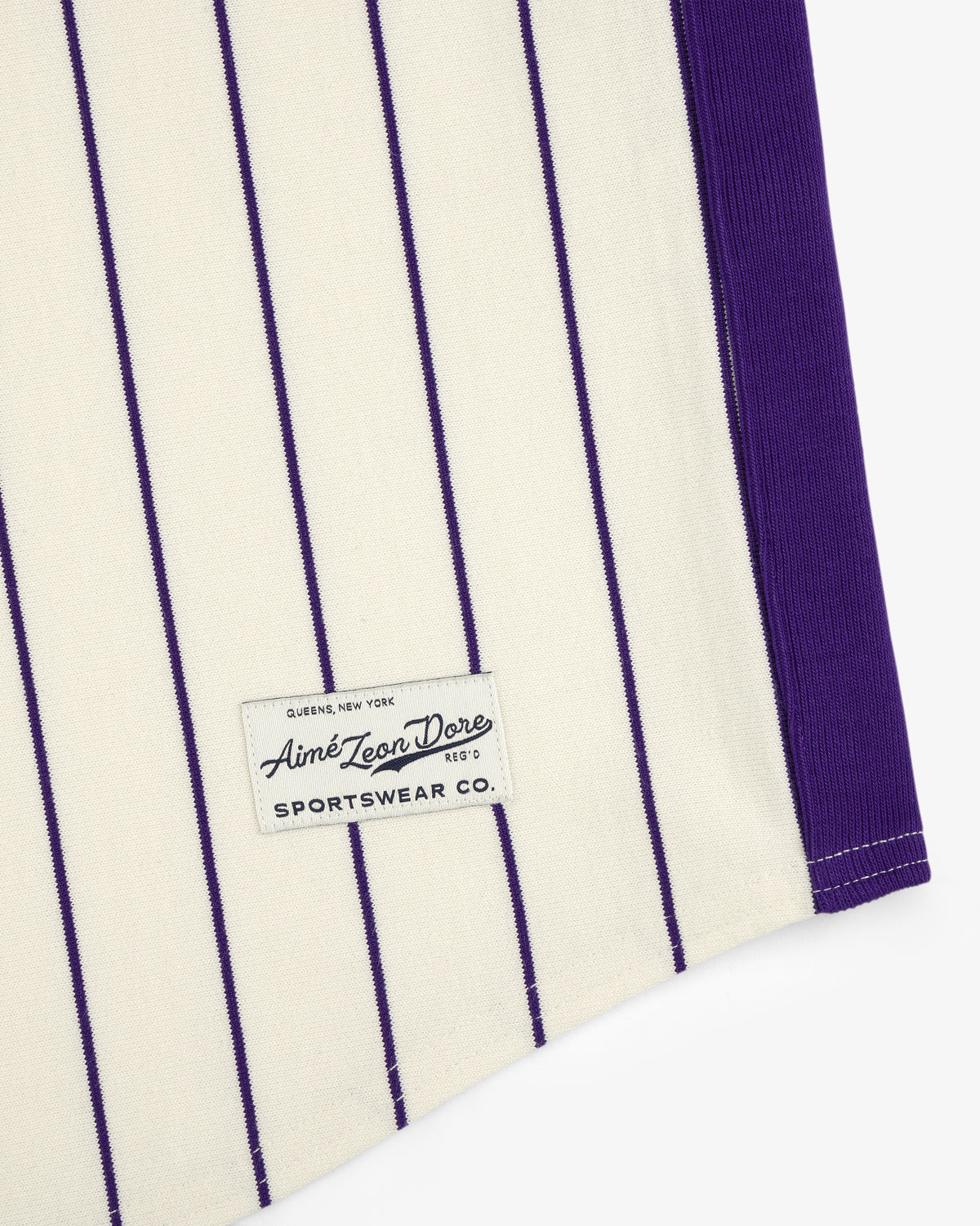 Cream fabric with vertical purple pinstripes and an Aimé Baseball Jersey label near the hem.