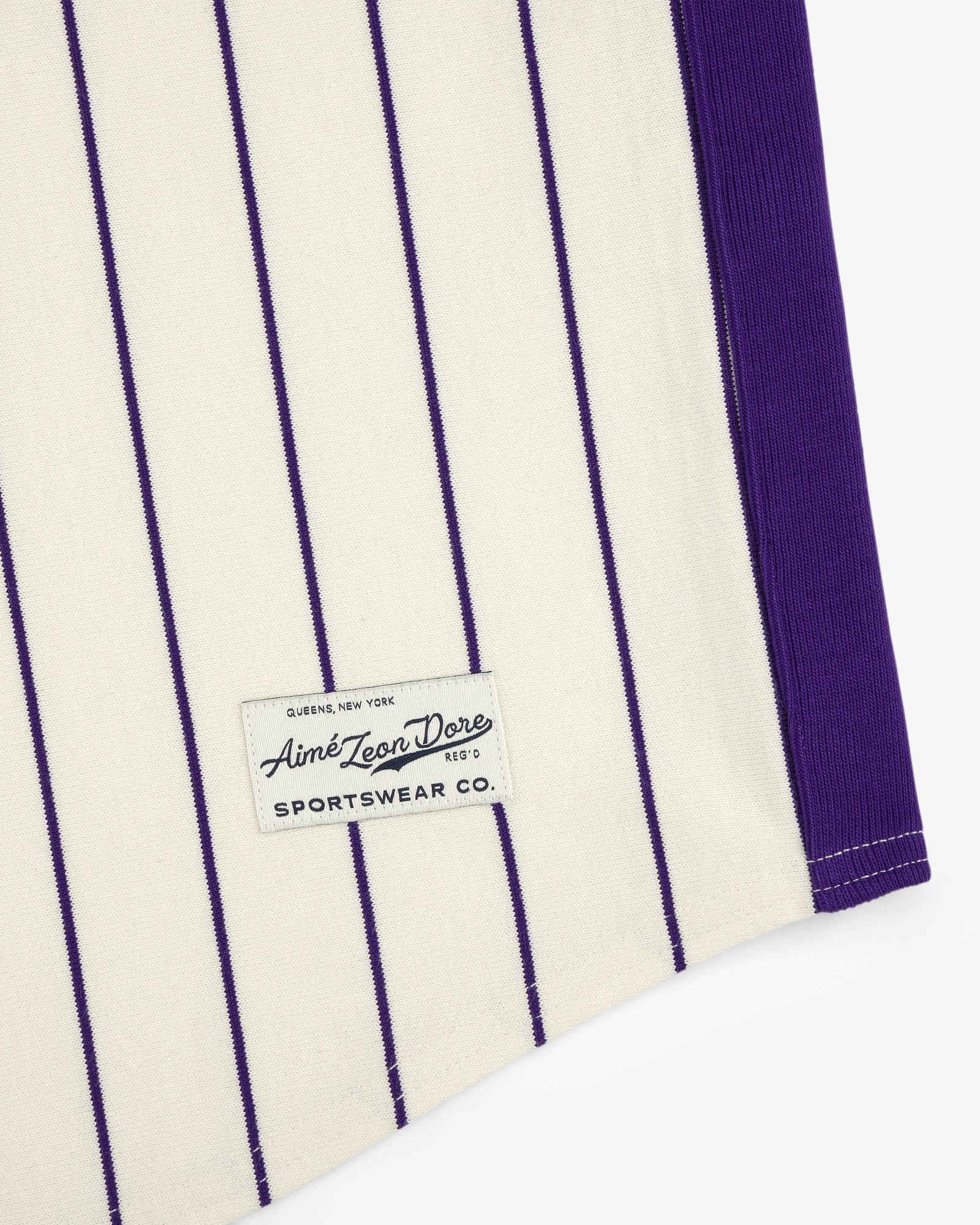 Cream fabric with vertical purple pinstripes and an Aimé Baseball Jersey label near the hem.