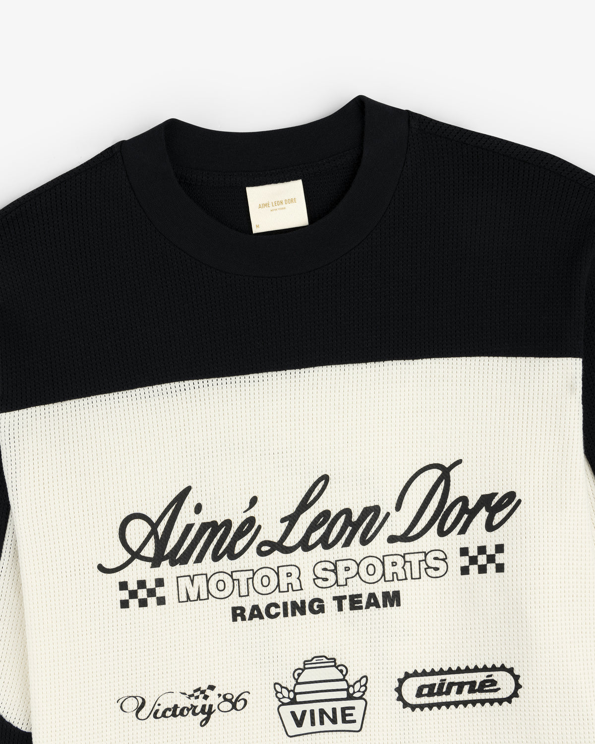 Close-up of a black and white Long-Sleeve Mesh Enduro Tee by Aimé Leon Dore, featuring logos and front text.