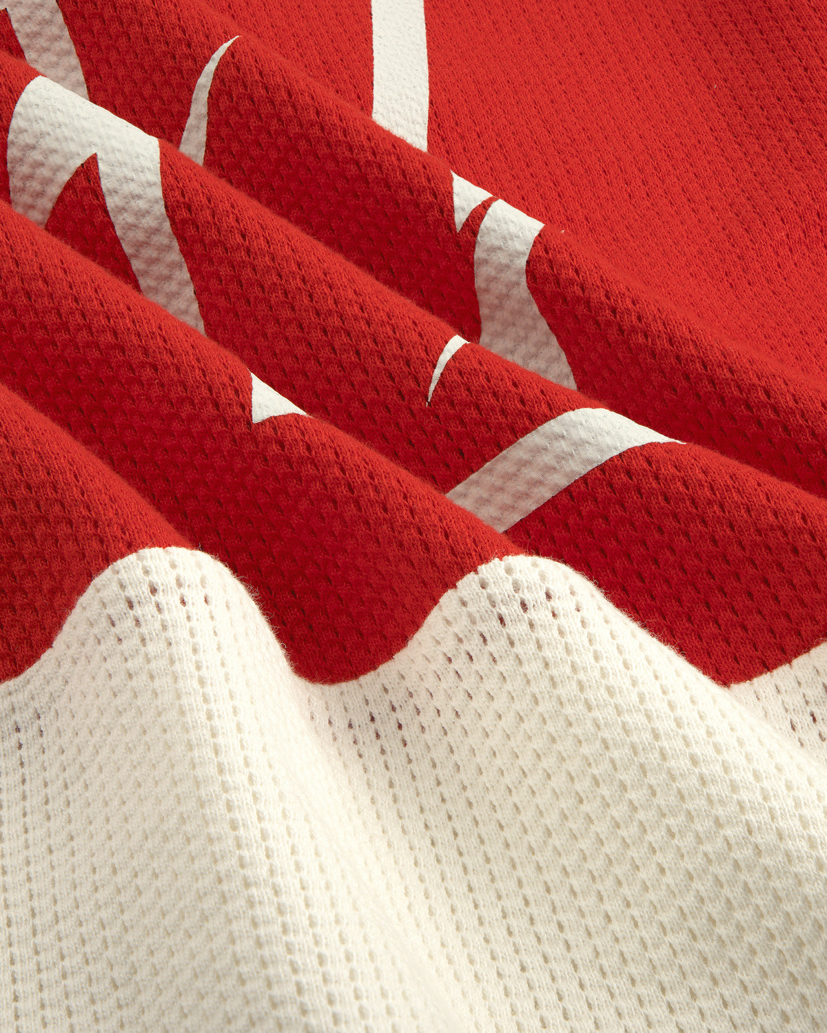 Close-up of the Long-Sleeve Mesh Enduro Tee in red and white with a partial white graphic design.