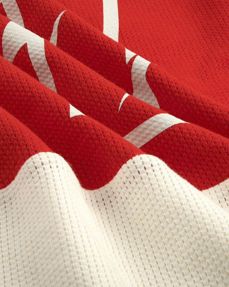 Close-up of the Long-Sleeve Mesh Enduro Tee in red and white with a partial white graphic design.