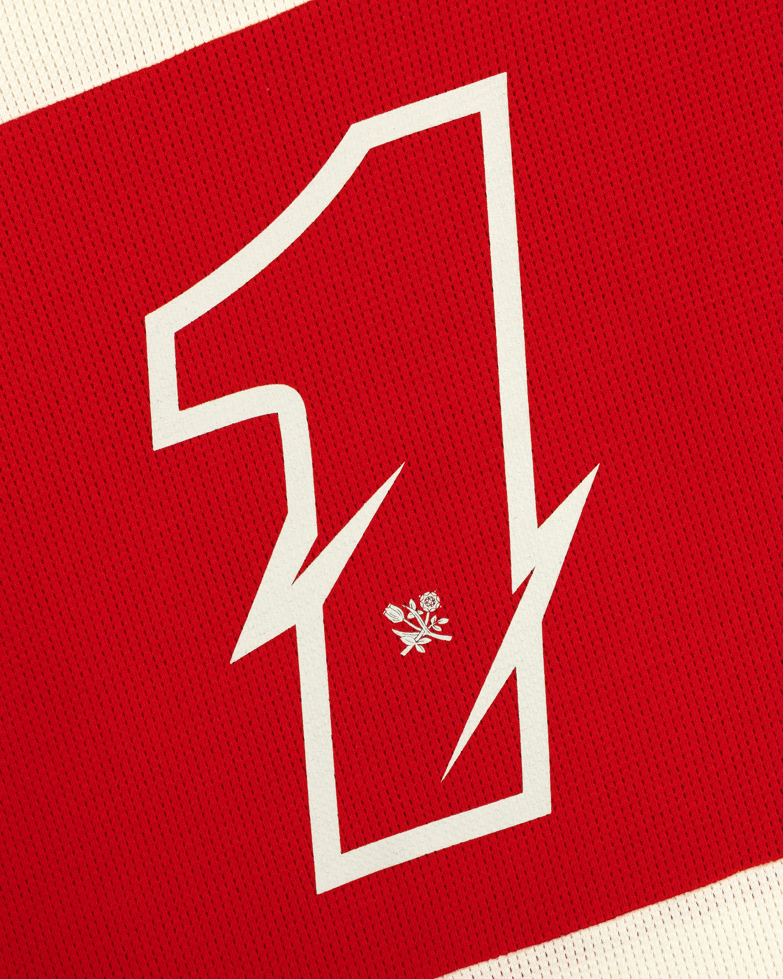 A large white number 1 with a lightning bolt and rose on red fabric of the Long-Sleeve Mesh Enduro Tee.