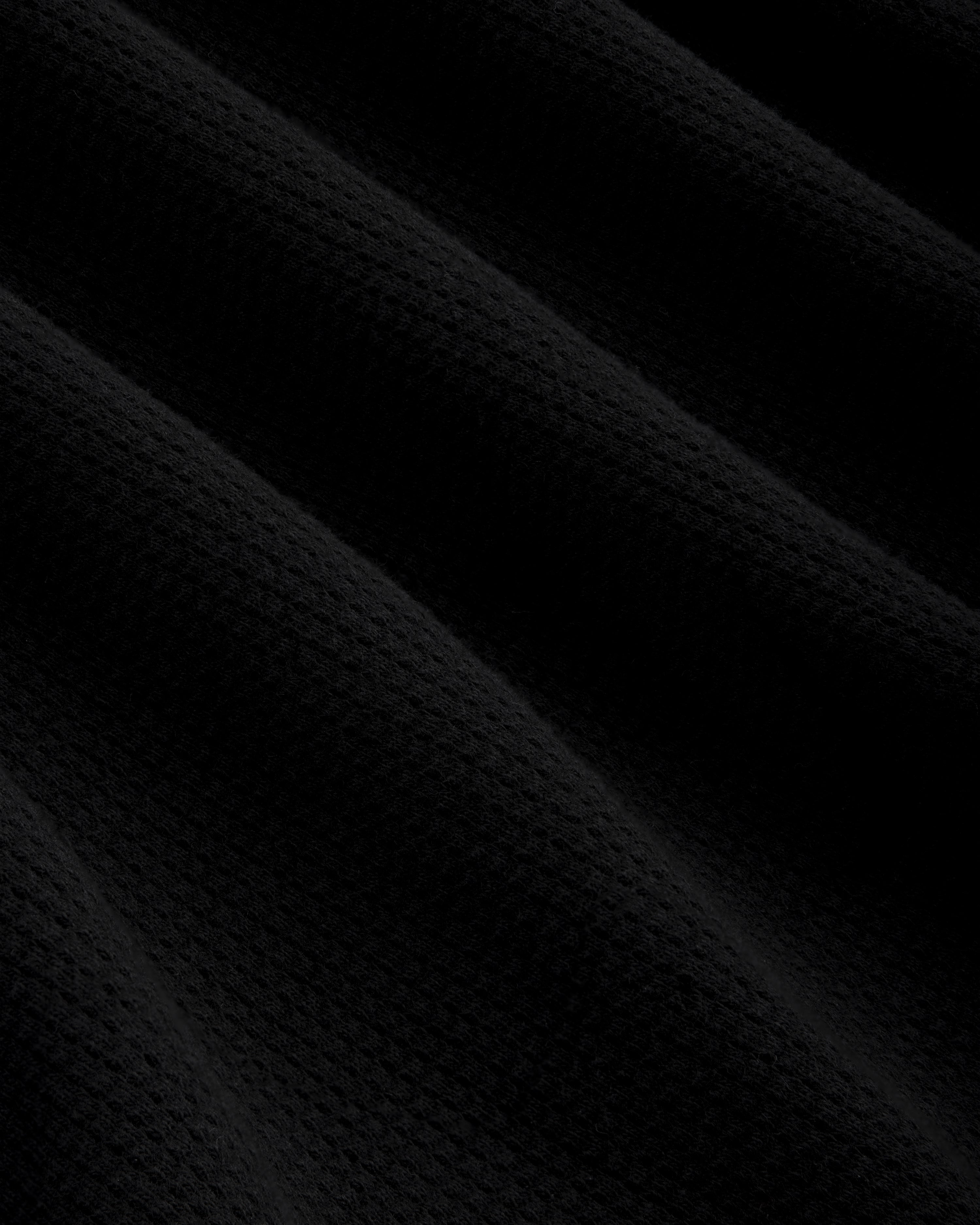 Close-up of Mesh Muscle Tank's black mesh fabric with soft, diagonal folds and gentle, subtle shadows.