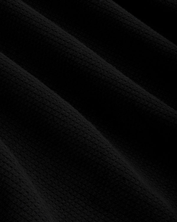 Close-up of Mesh Muscle Tank's black mesh fabric with soft, diagonal folds and gentle, subtle shadows.