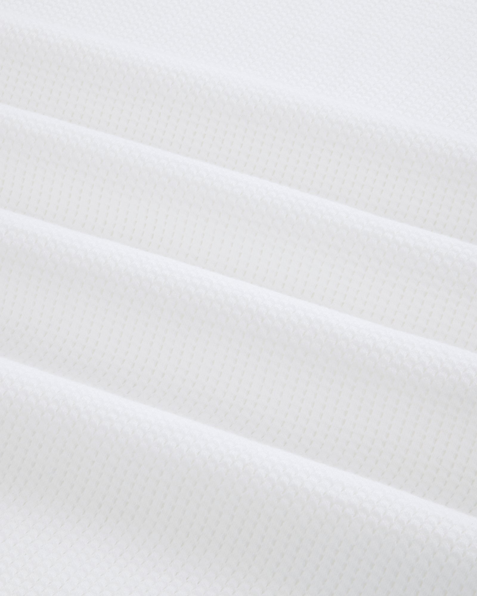 Close-up of white Mesh Muscle Tank fabric with soft, evenly spaced diagonal folds.