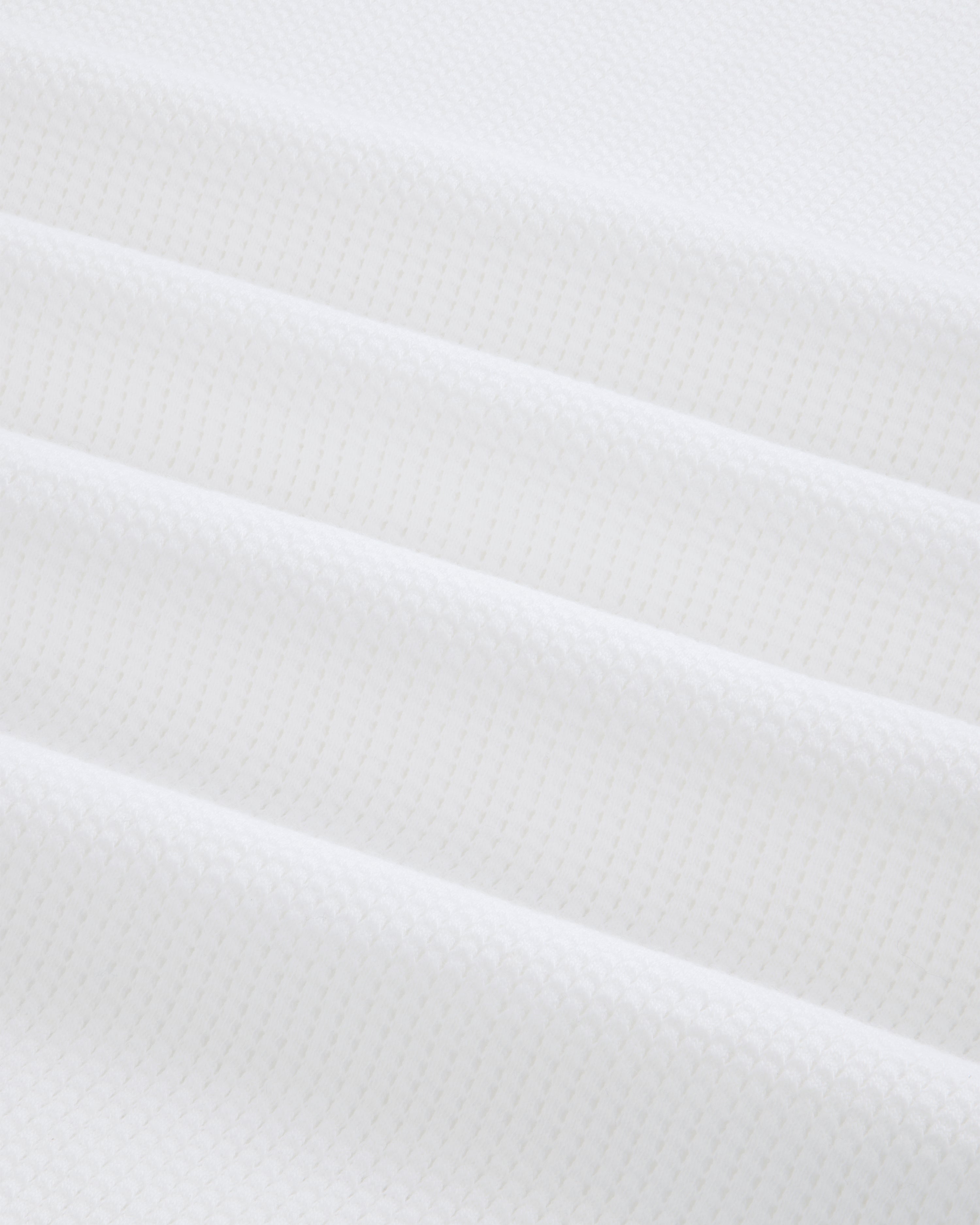 Close-up of white Mesh Muscle Tank fabric with soft, evenly spaced diagonal folds.